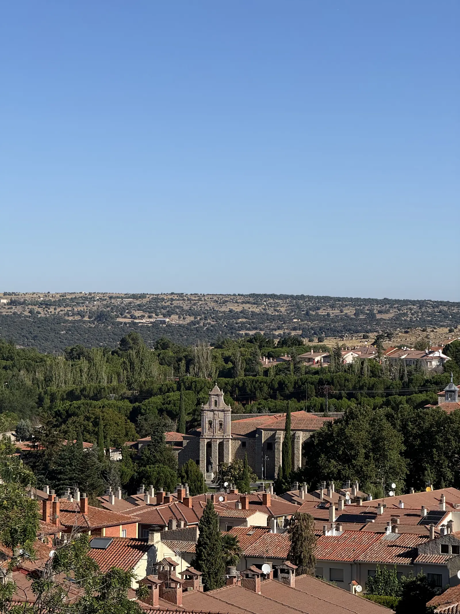 Espadaña del monasterio de la Encarnación de Ávila entre cipreses y tejados rojos del norte de la ciudad. Foto propia La Maleta Inquieta, septiembre 2026.