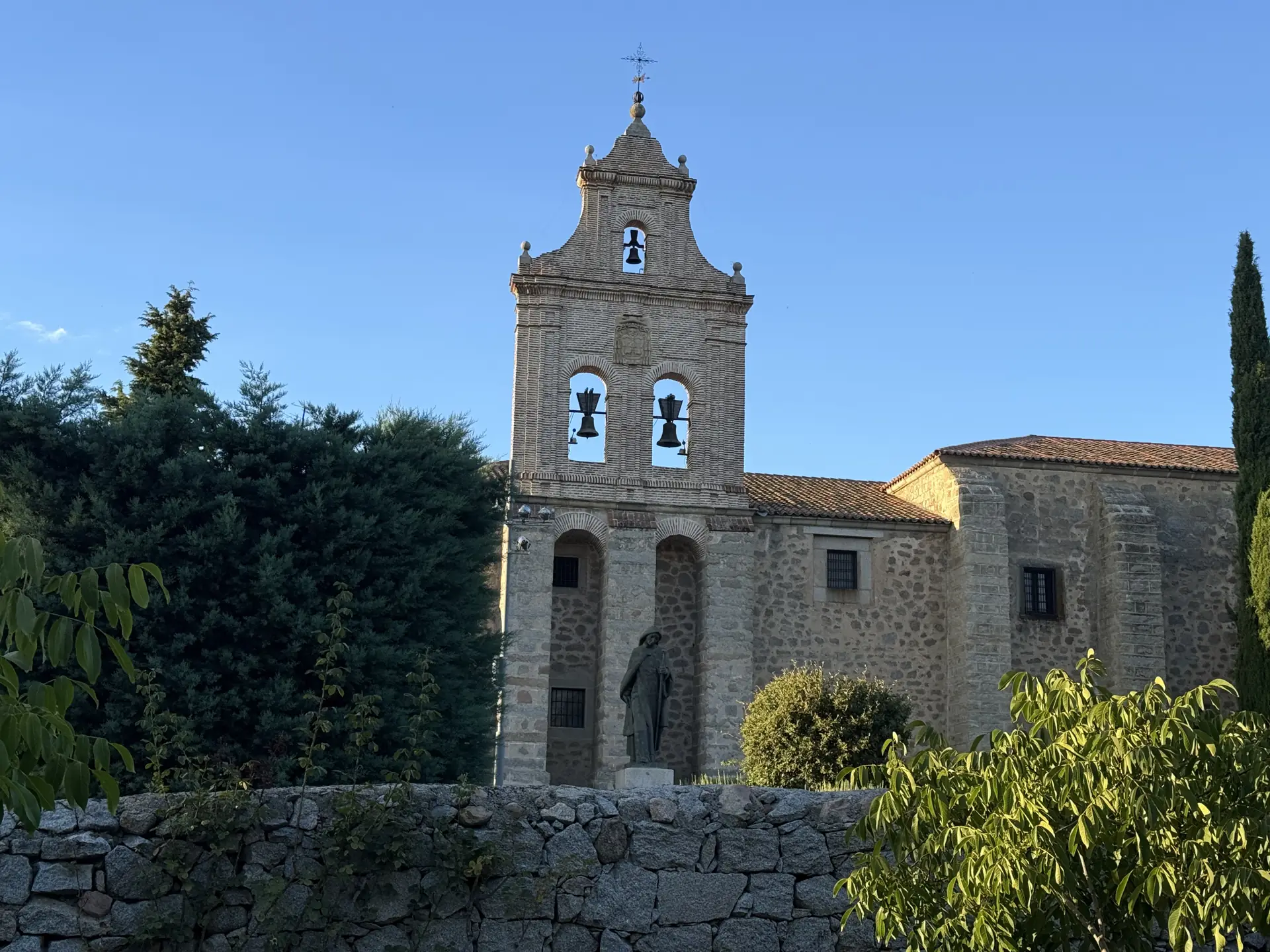 Iglesia del monasterio de la Encarnación de Ávila con su espadaña y la estatua de Santa Teresa tras la tapia. Foto propia La Maleta Inquieta, septiembre 2026.