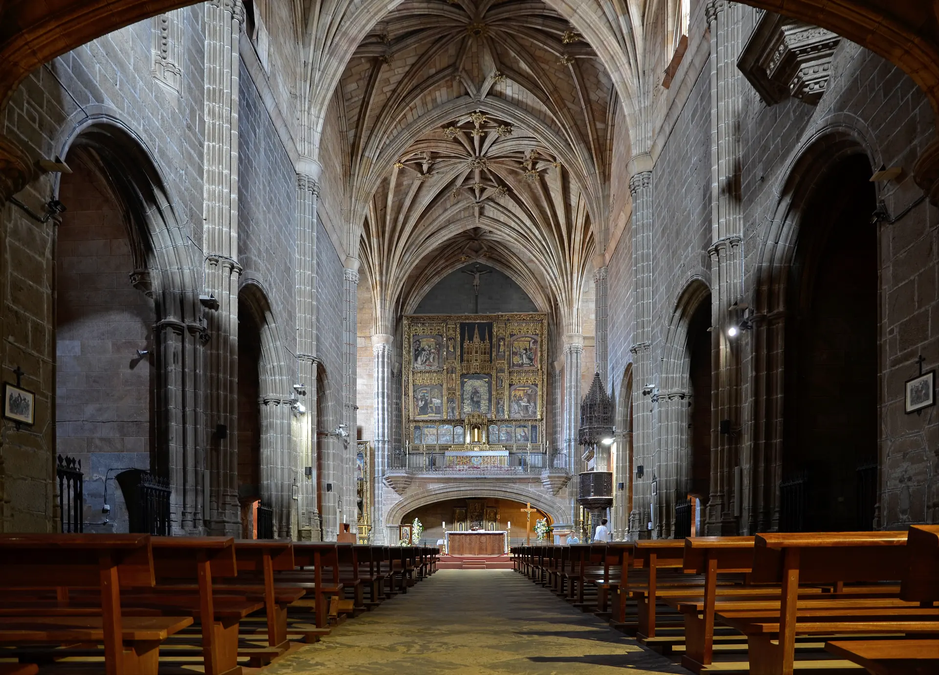 Nave gótica de la iglesia de Santo Tomás de Ávila, con bóvedas de crucería y bancos, y el retablo dorado de Berruguete en la capilla mayor elevada