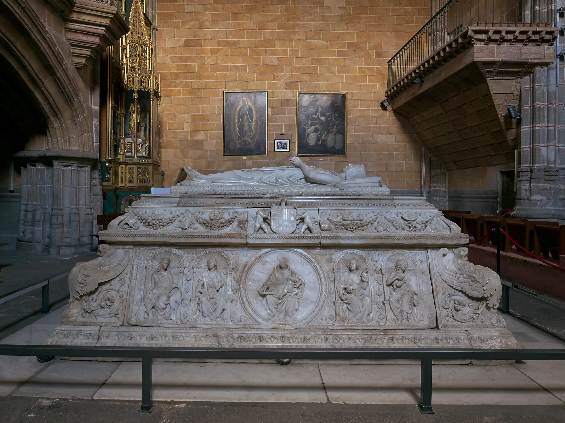 Sepulcro de mármol blanco del príncipe don Juan en Santo Tomás de Ávila, con la figura yacente sobre relieves de santos y el escudo real