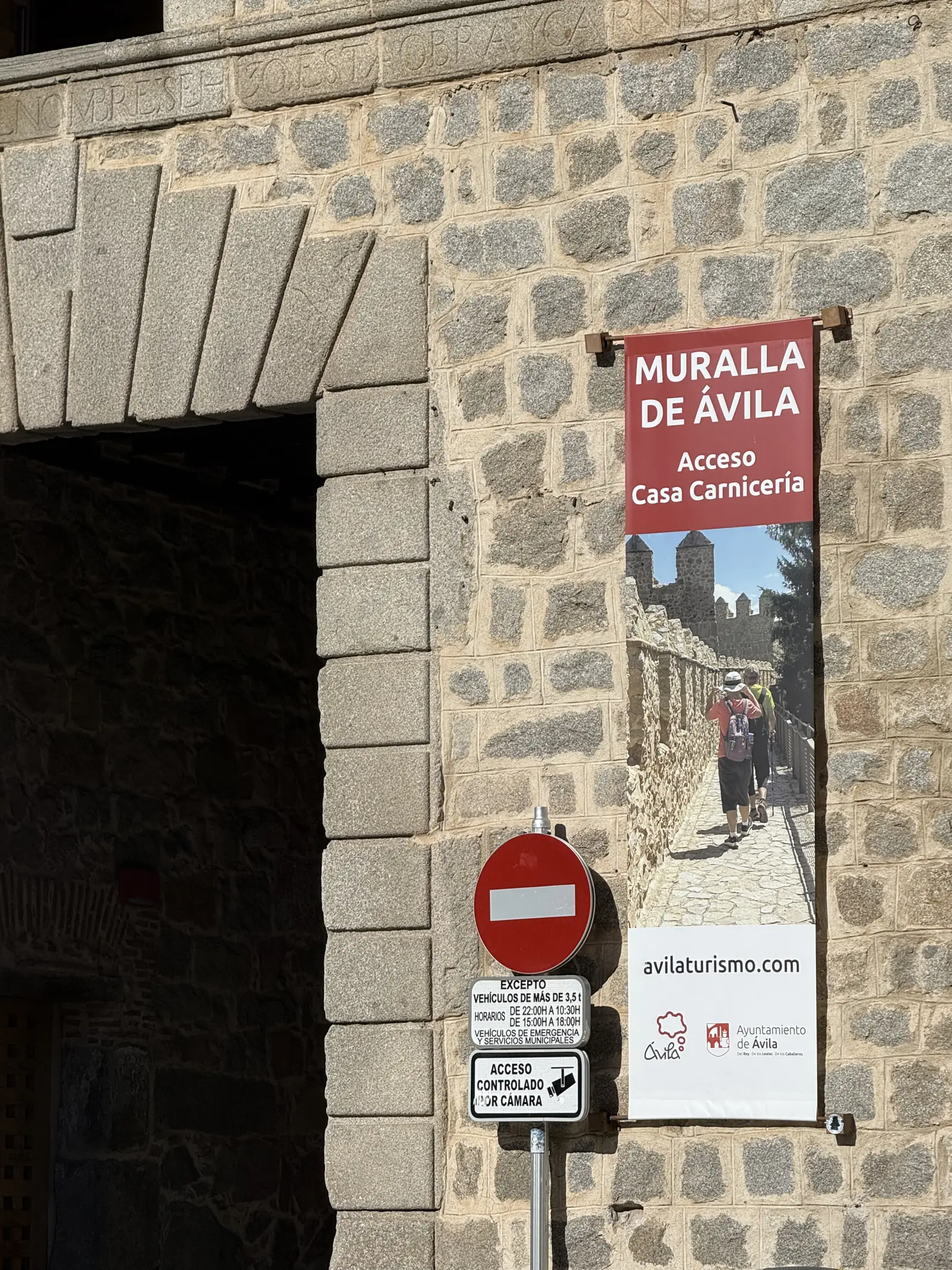 Cartel de acceso a la muralla de Ávila por la Casa Carnicería junto a una señal de tráfico con horarios. Foto propia La Maleta Inquieta, septiembre 2026