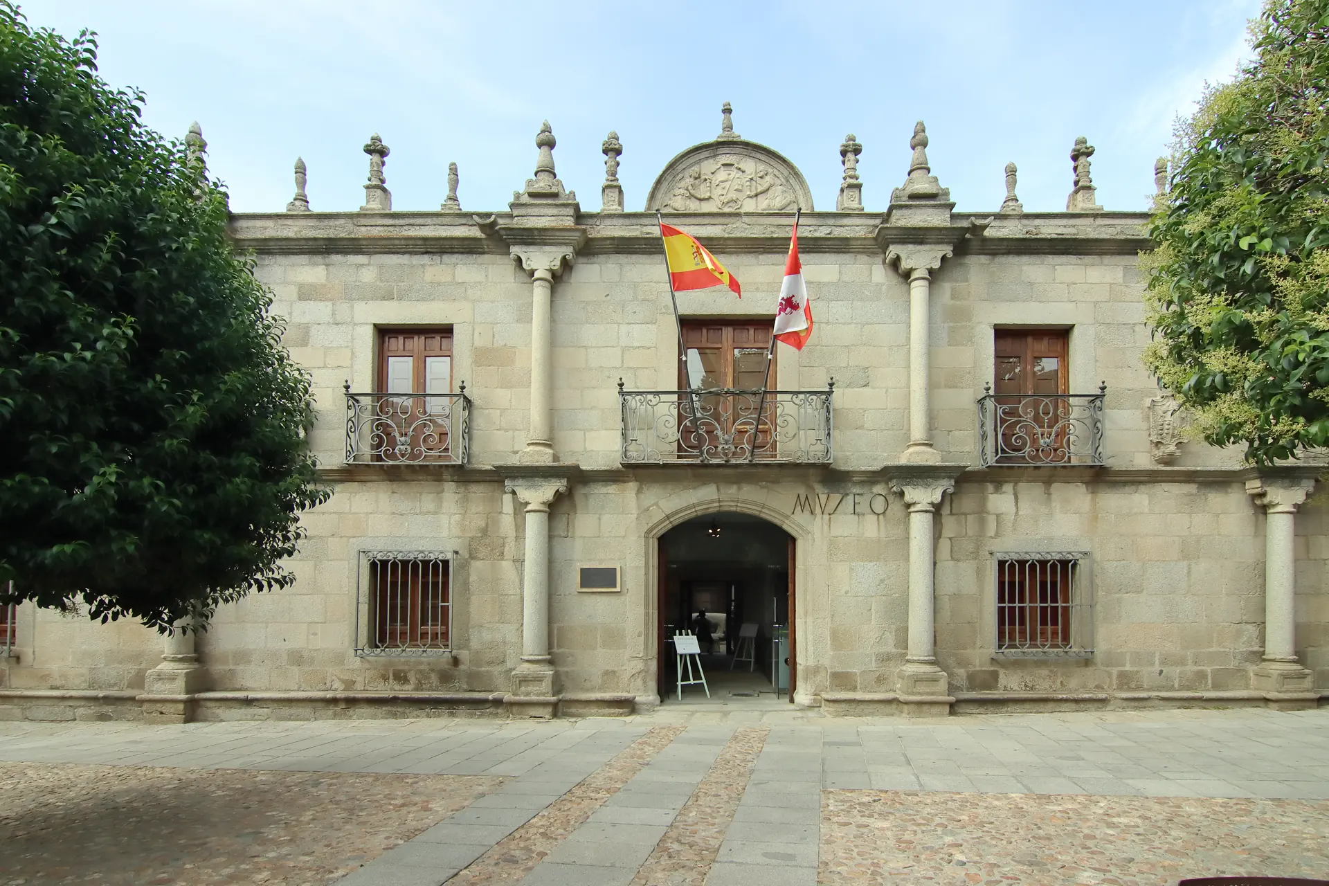 Fachada renacentista de granito de la Casa de los Deanes, sede del Museo de Ávila, con pináculos, frontón con escudo, balcones de forja y la puerta de entrada