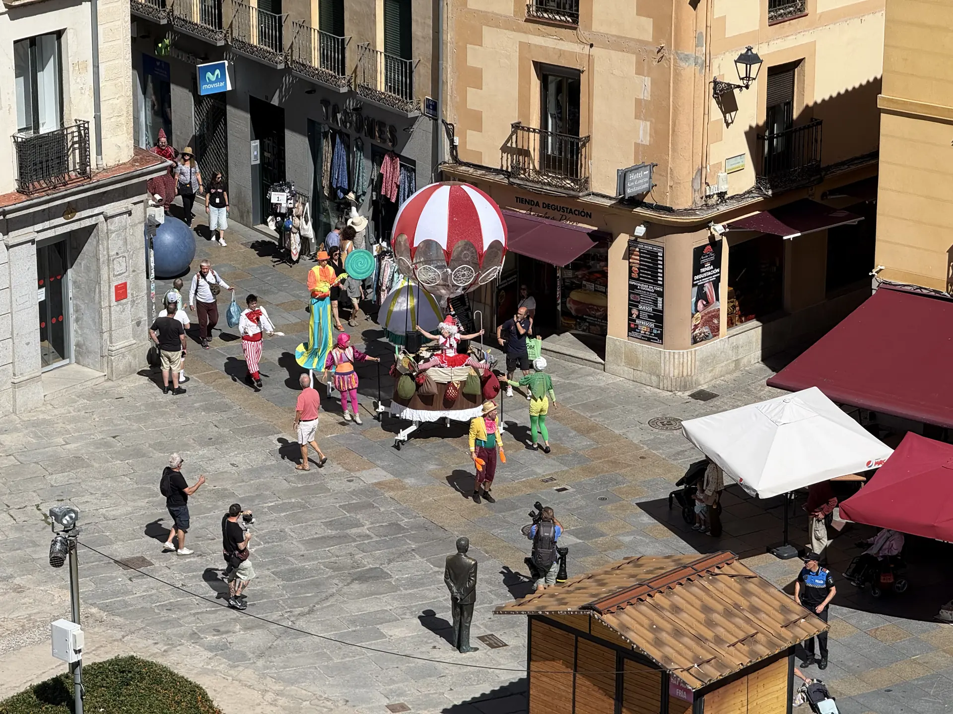 Pasacalles con zancudos, malabarista y carroza globo junto a la plaza de Santa Teresa de Ávila, desde arriba. Foto propia La Maleta Inquieta, septiembre 2026.
