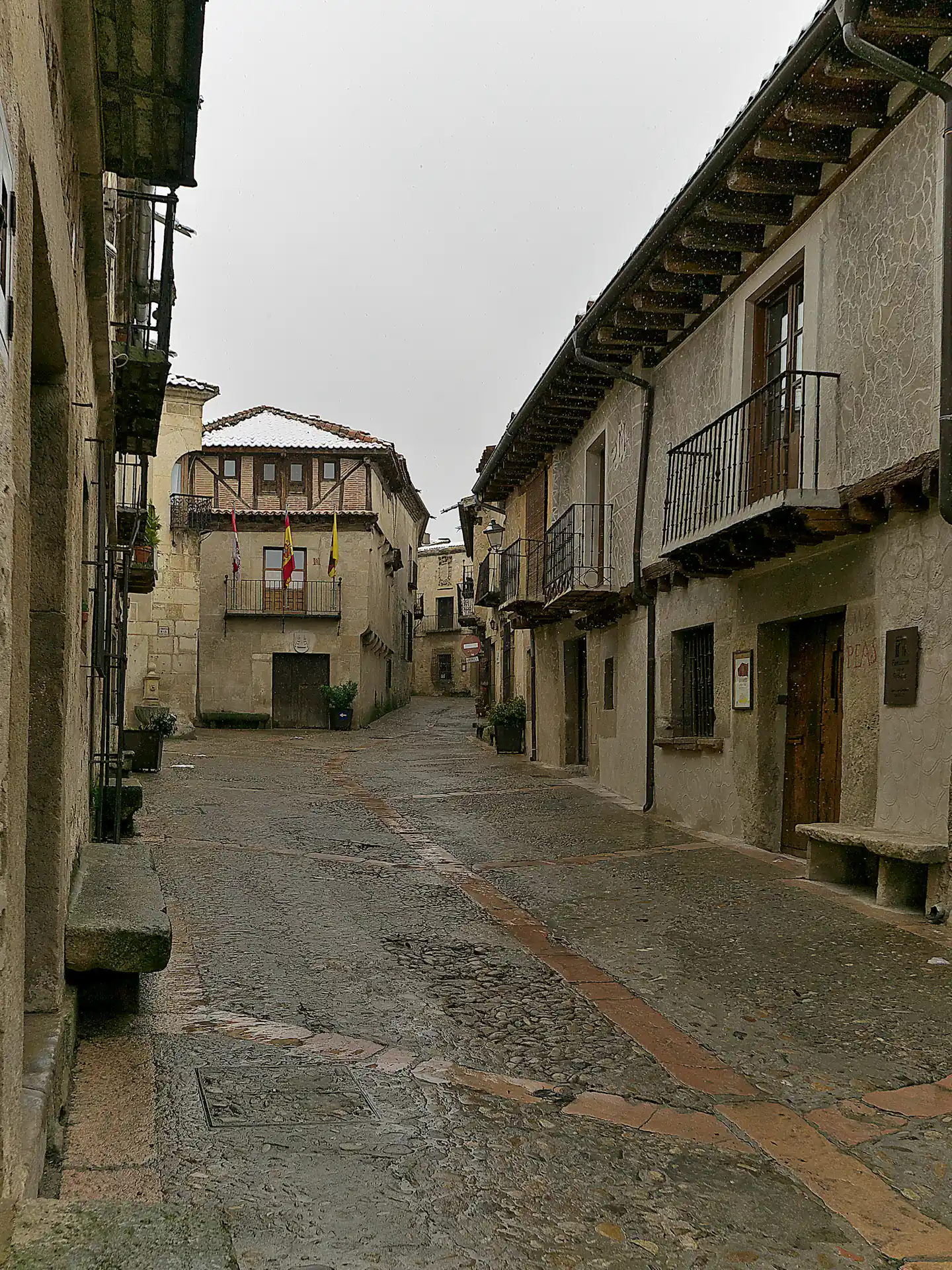 Calle empedrada de Pedraza entre casonas de piedra con escudos, en la villa amurallada de Segovia.