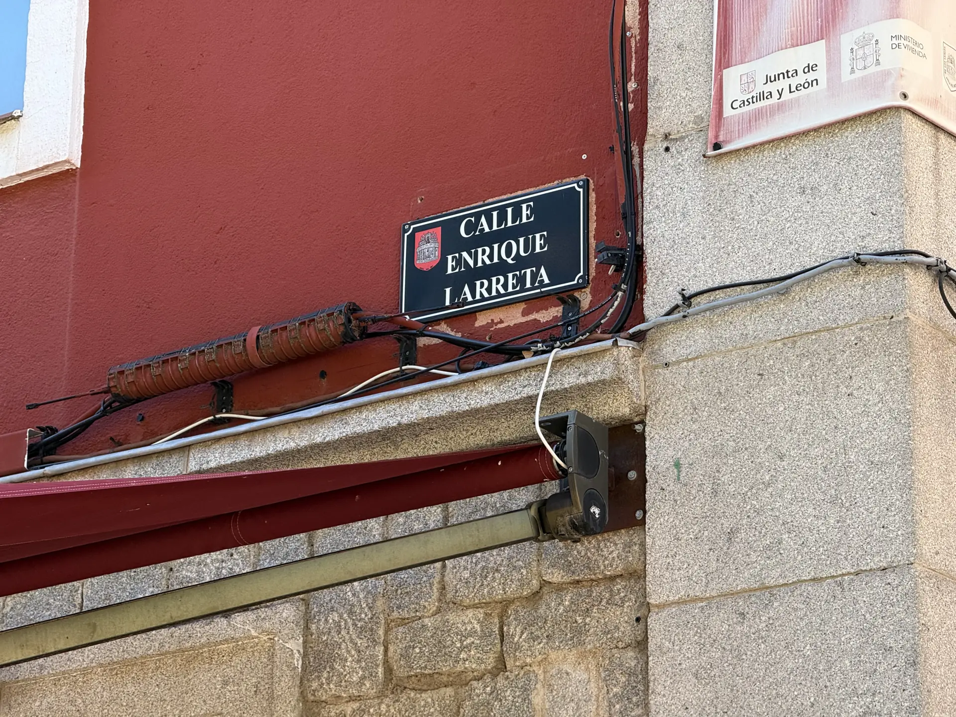 Placa de la calle Enrique Larreta con el escudo de Ávila sobre una fachada roja, junto al Mercado Chico. Foto propia La Maleta Inquieta, septiembre 2026.