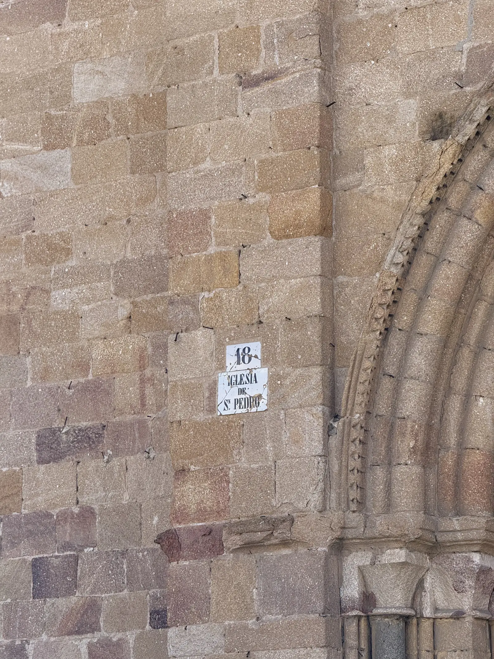 Placa esmaltada 18 Iglesia de San Pedro junto a las arquivoltas de su portada, sobre sillares bicolores en Ávila. Foto propia La Maleta Inquieta, septiembre 2026.