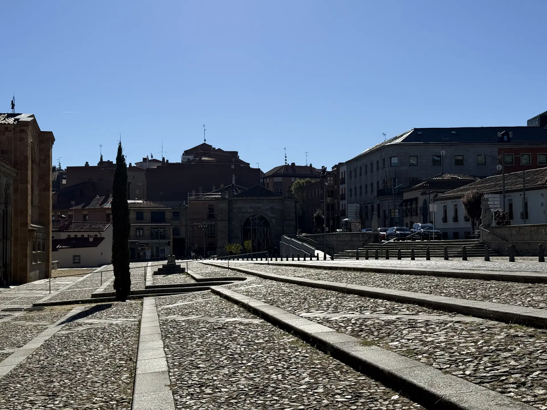 Plaza de San Vicente de Ávila, con empedrado de cantos, bandas de granito y un ciprés junto a la basílica. Foto propia La Maleta Inquieta, septiembre 2026
