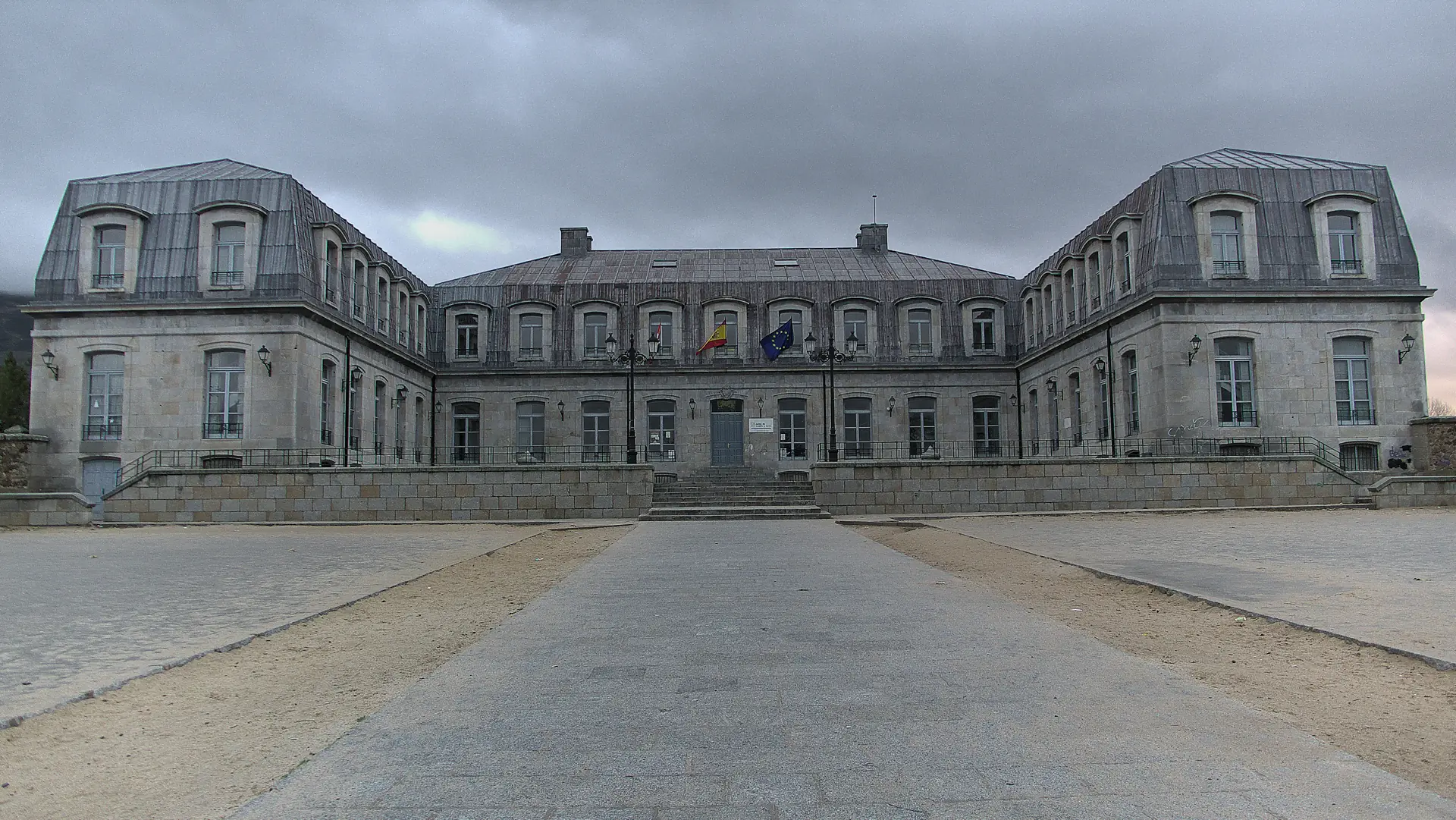 Fachada del palacio de los duques de Alba en Piedrahíta, de granito con dos alas laterales y tejados de pizarra abuhardillados, bajo un cielo nublado