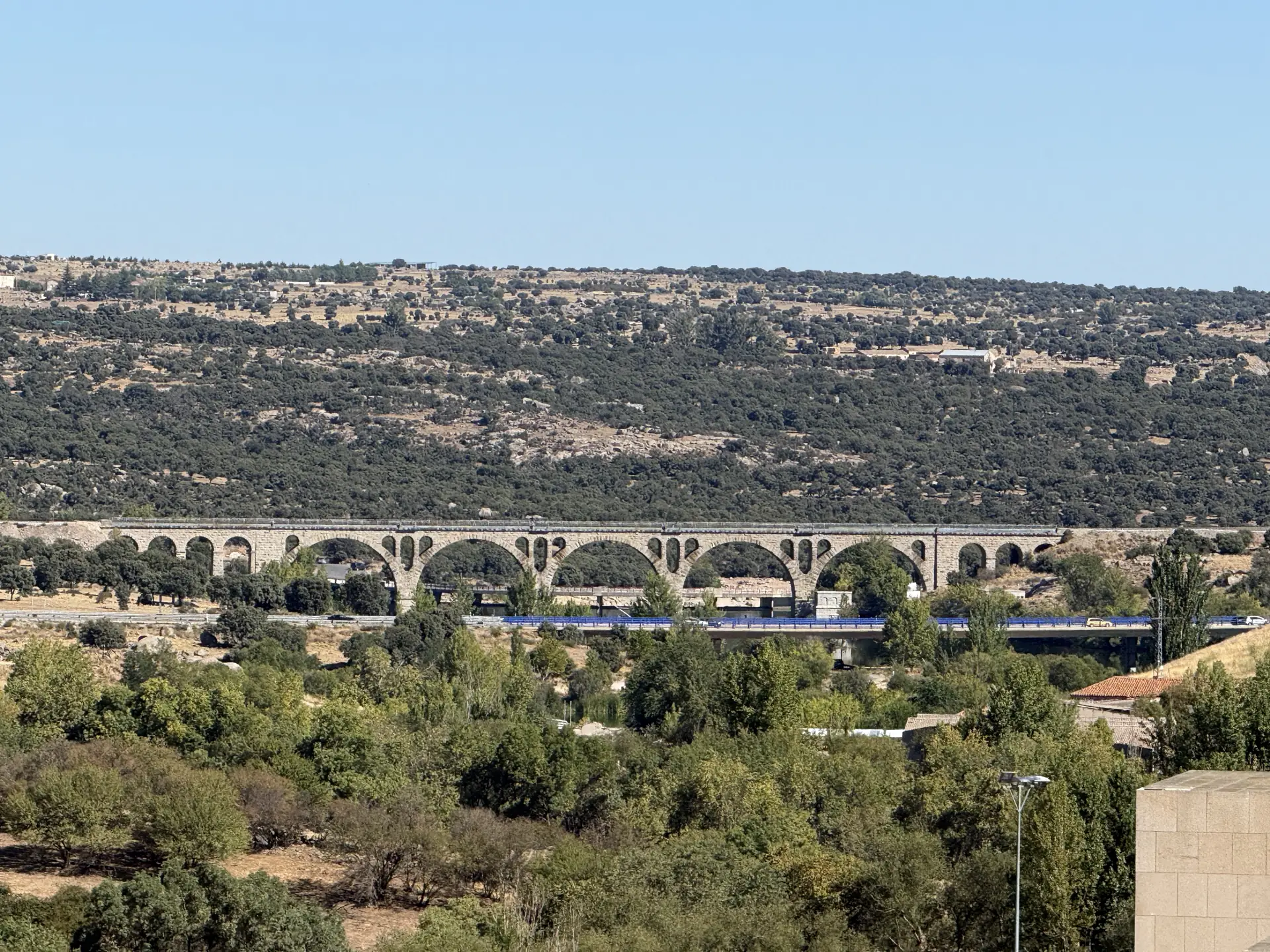 Puente de arcos de granito del ferrocarril Ávila-Salamanca sobre el valle del Adaja, con la dehesa detrás. Foto propia La Maleta Inquieta, septiembre 2026.