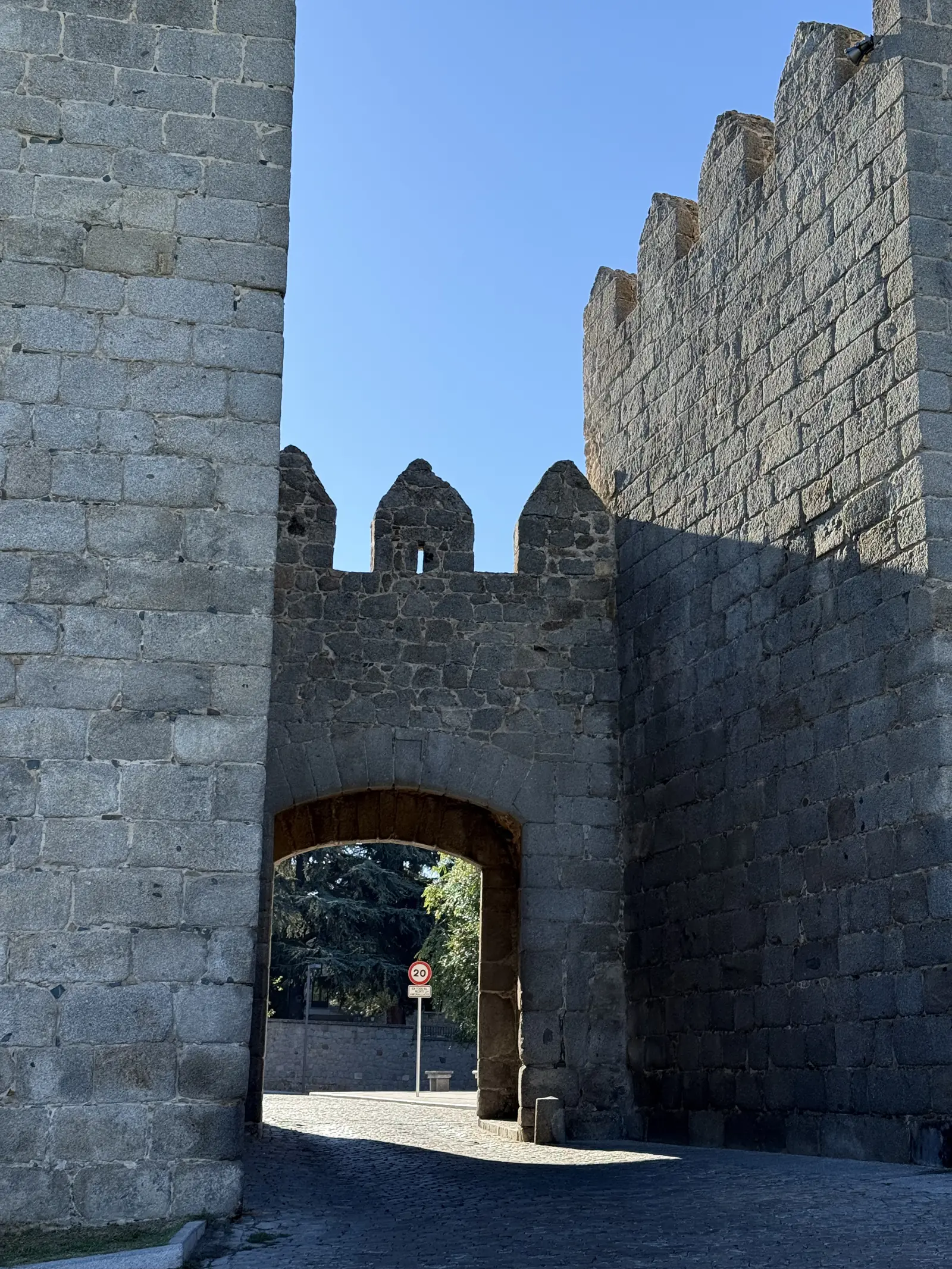 Arco de la Puerta del Carmen entre torreones almenados de la muralla norte de Ávila, con sombra en el empedrado. Foto propia La Maleta Inquieta, septiembre 2026.