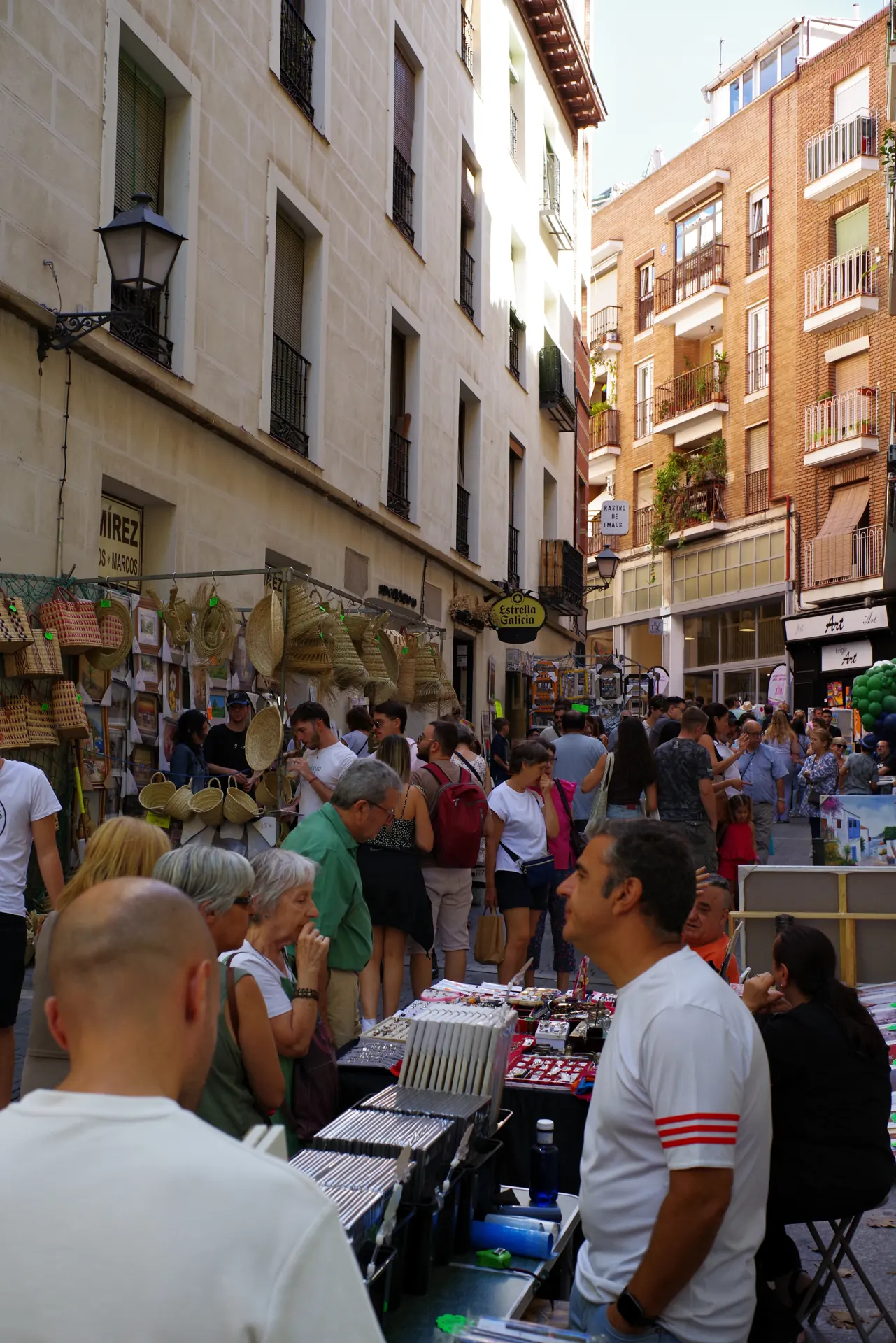 Puestos de cestas, cuadros y bisutería con mucha gente en la calle de San Cayetano durante el Rastro de Madrid