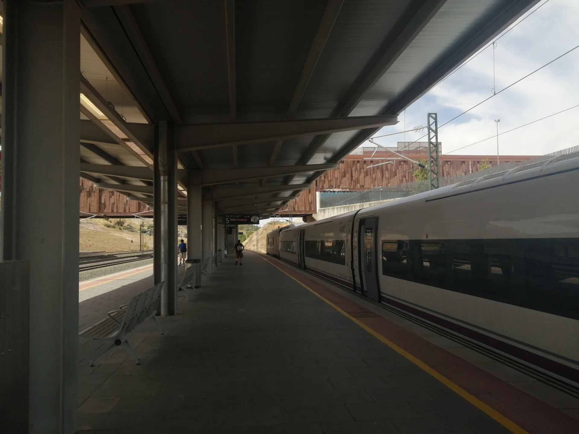 Tren AVE parado en el andén cubierto de la estación Cuenca-Fernando Zóbel, con la pasarela de la estación al fondo