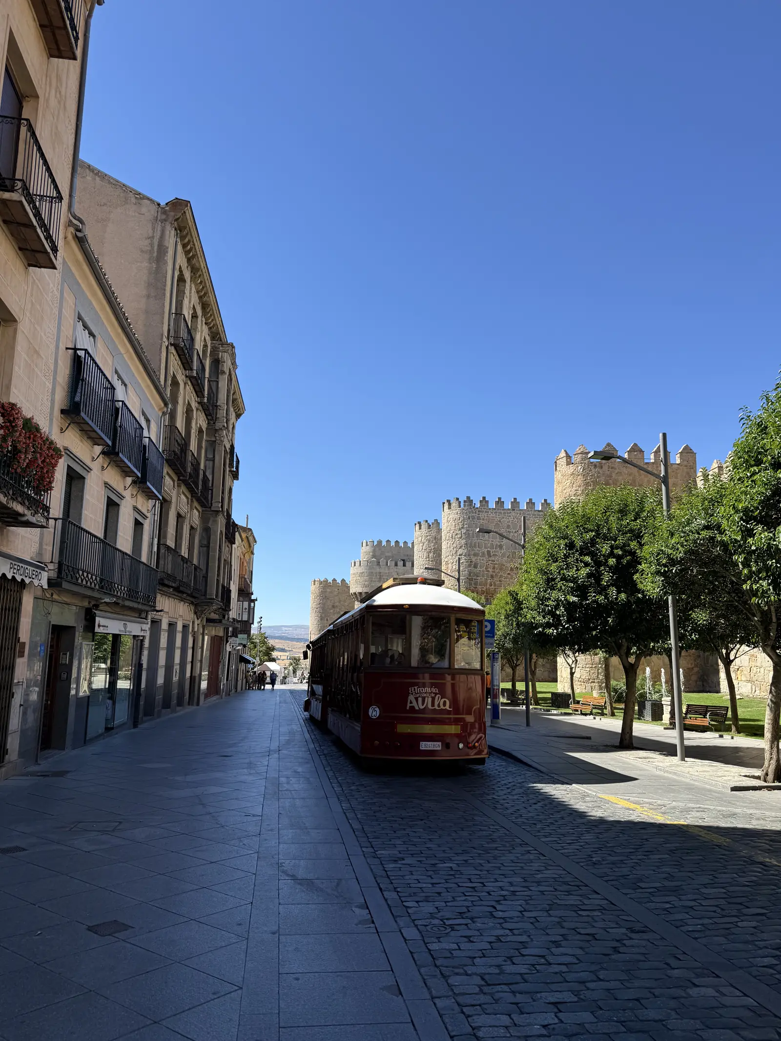 Tren turístico rojo de Ávila por el empedrado de la calle San Segundo, con los cubos de la muralla al fondo. Foto propia La Maleta Inquieta, septiembre 2026.