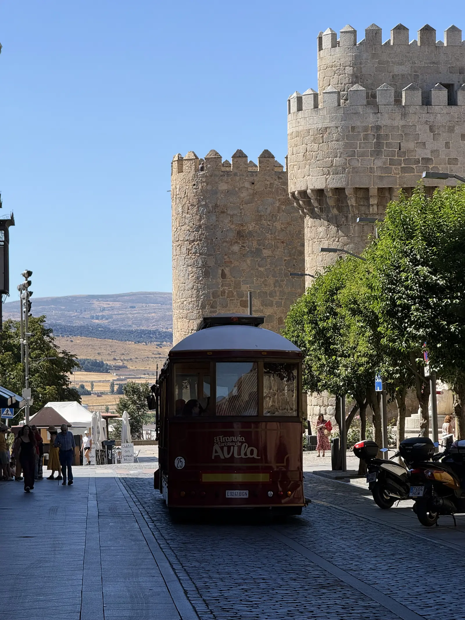 Tren turístico de Ávila ante los torreones de la Puerta del Alcázar, con terrazas y pizarras de chuletón. Foto propia La Maleta Inquieta, septiembre 2026.