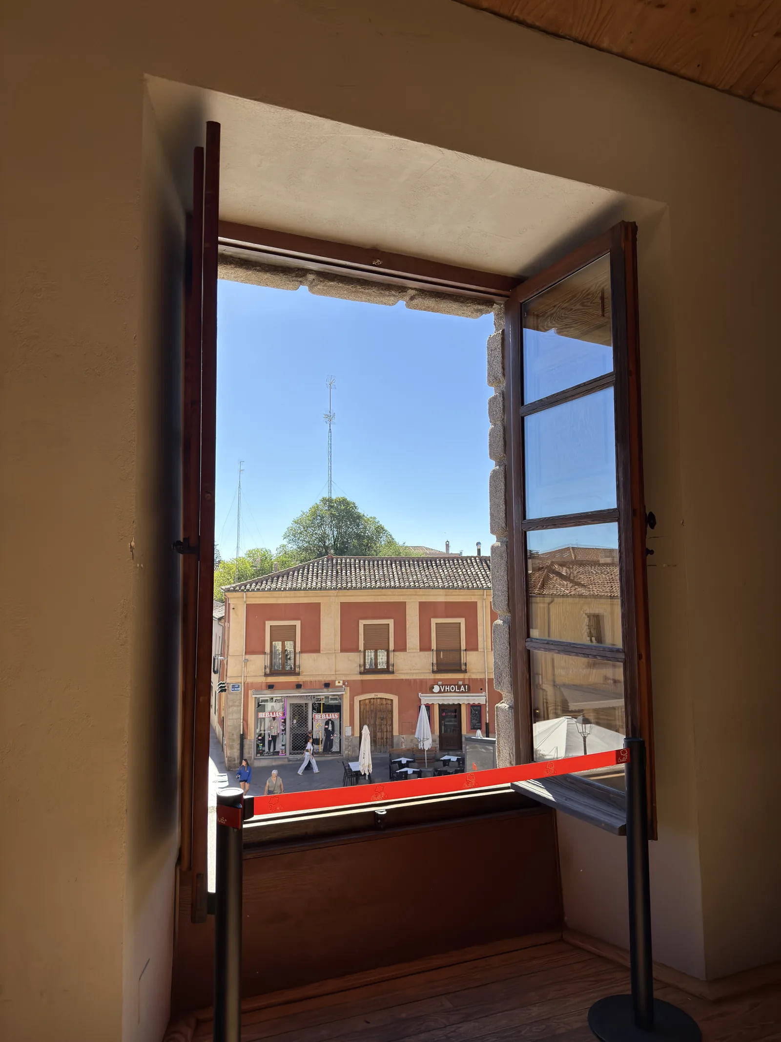 Ventana abierta del acceso a la muralla de Ávila, con cinta de visitas y una calle con terraza al fondo. Foto propia La Maleta Inquieta, septiembre 2026.