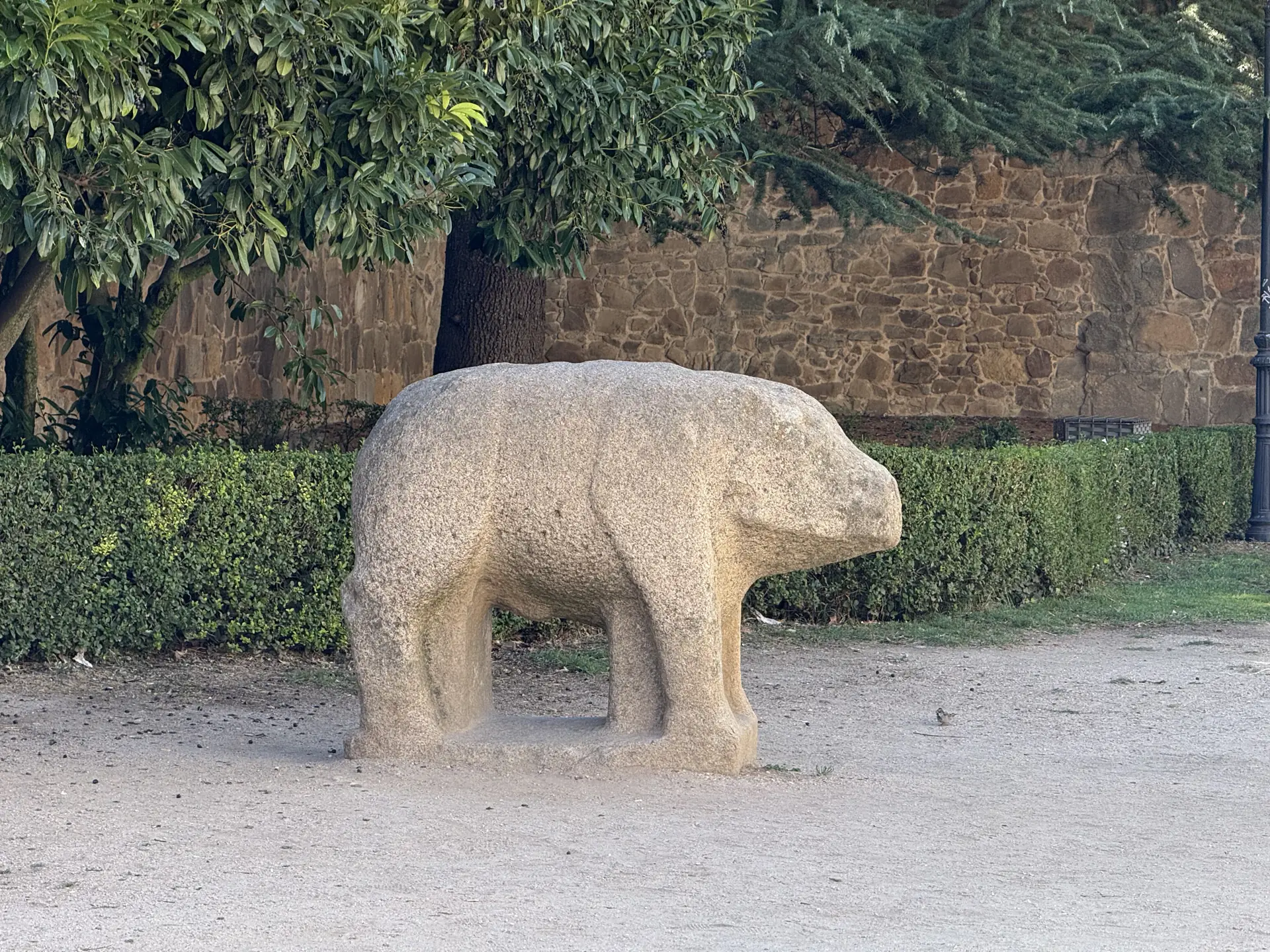 Verraco vettón de granito en un jardín de tierra al pie de la muralla, junto a la plaza de Santa Teresa de Ávila. Foto propia La Maleta Inquieta, septiembre 2026.