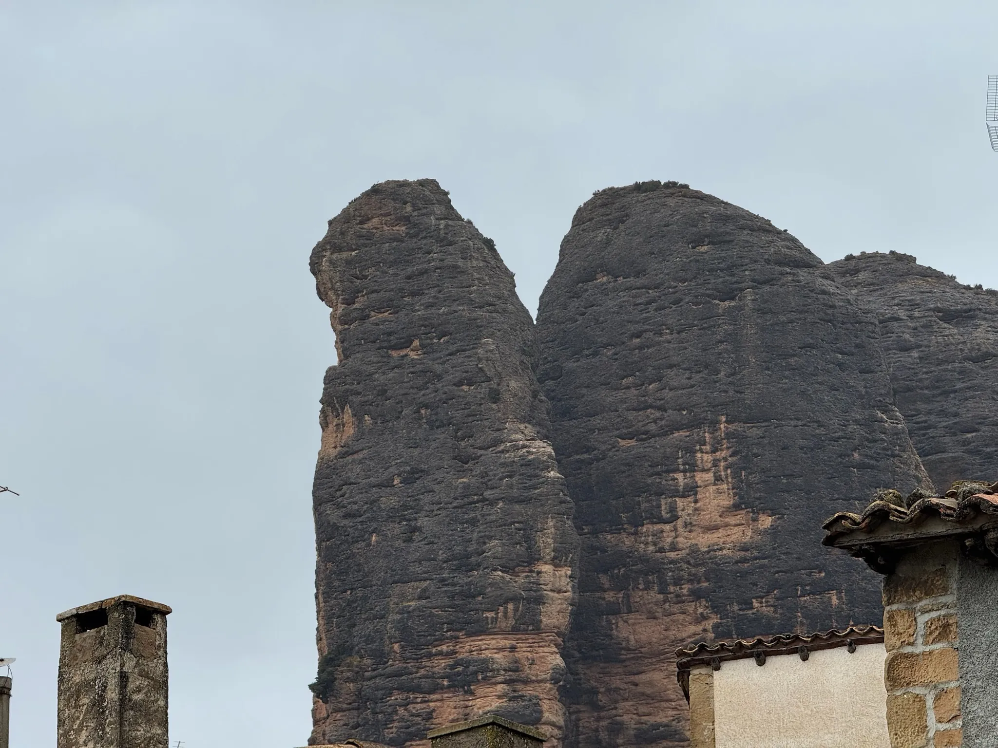 Detalle de los mallos de conglomerado de Agüero con tejados de casas en primer plano. Foto propia La Maleta Inquieta, octubre 2026