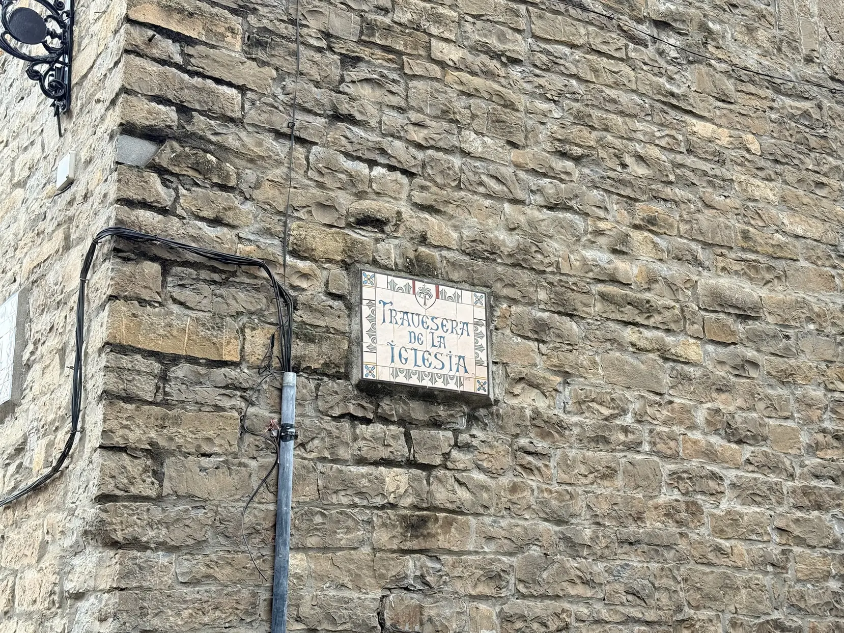 Placa cerámica en muro de piedra con el nombre Travesera de la Iglesia en Aínsa. Foto propia La Maleta Inquieta, octubre 2026