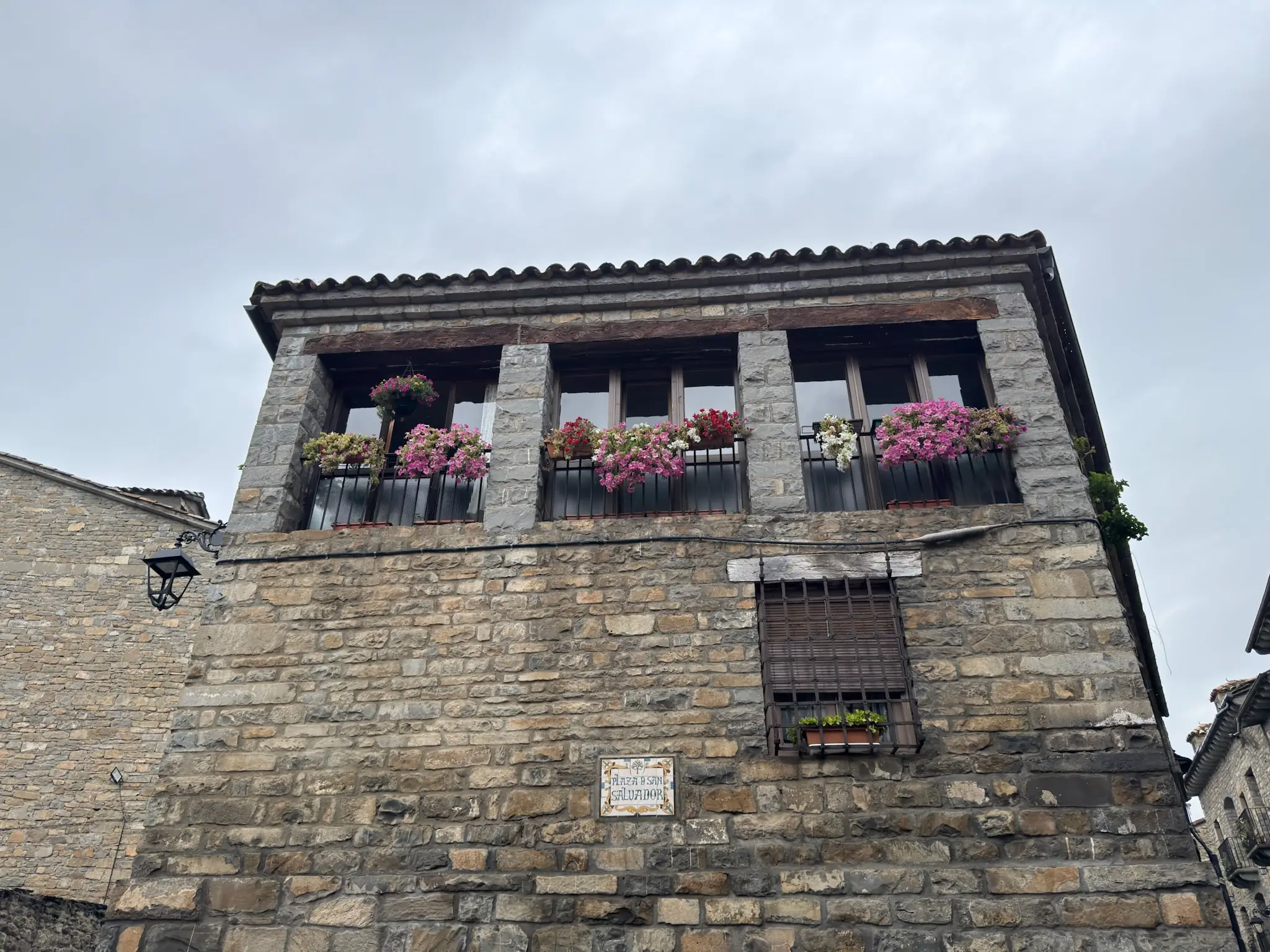Fachada de casa tradicional de piedra en Aínsa con galería de madera en piso superior y flores en balcones. Foto propia La Maleta Inquieta, octubre 2026