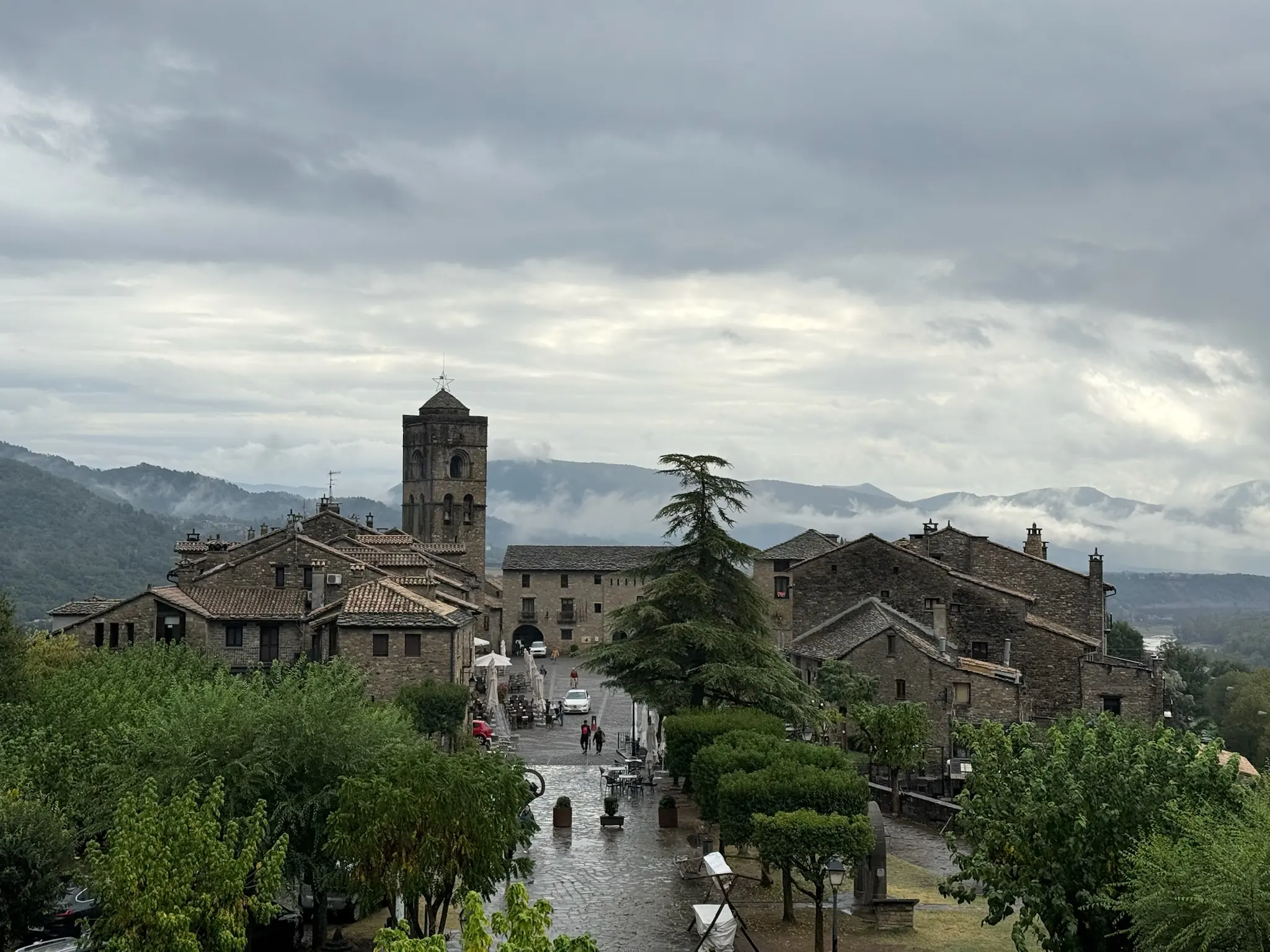 Vista de la plaza Mayor de Aínsa con la torre de la iglesia, casas medievales de piedra y montañas al fondo. Foto propia La Maleta Inquieta, octubre 2026