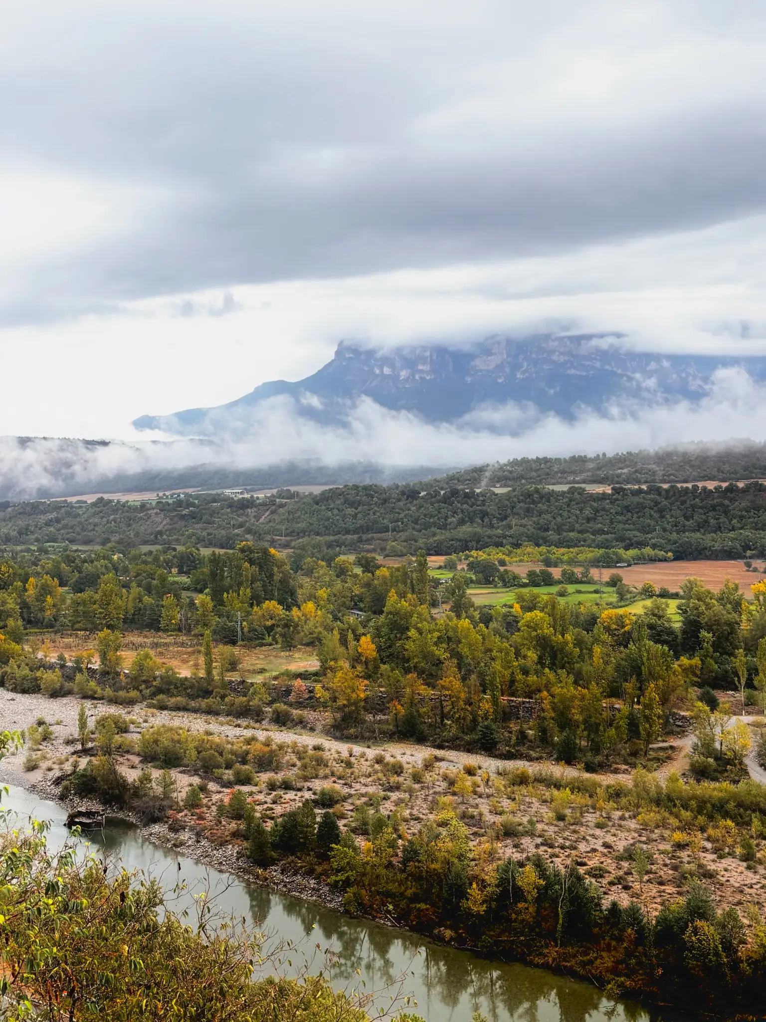 Valle del río con campos de cultivo y la Peña Montañesa envuelta en nubes al fondo, visto desde Aínsa en otoño. Foto propia La Maleta Inquieta, octubre 2026
