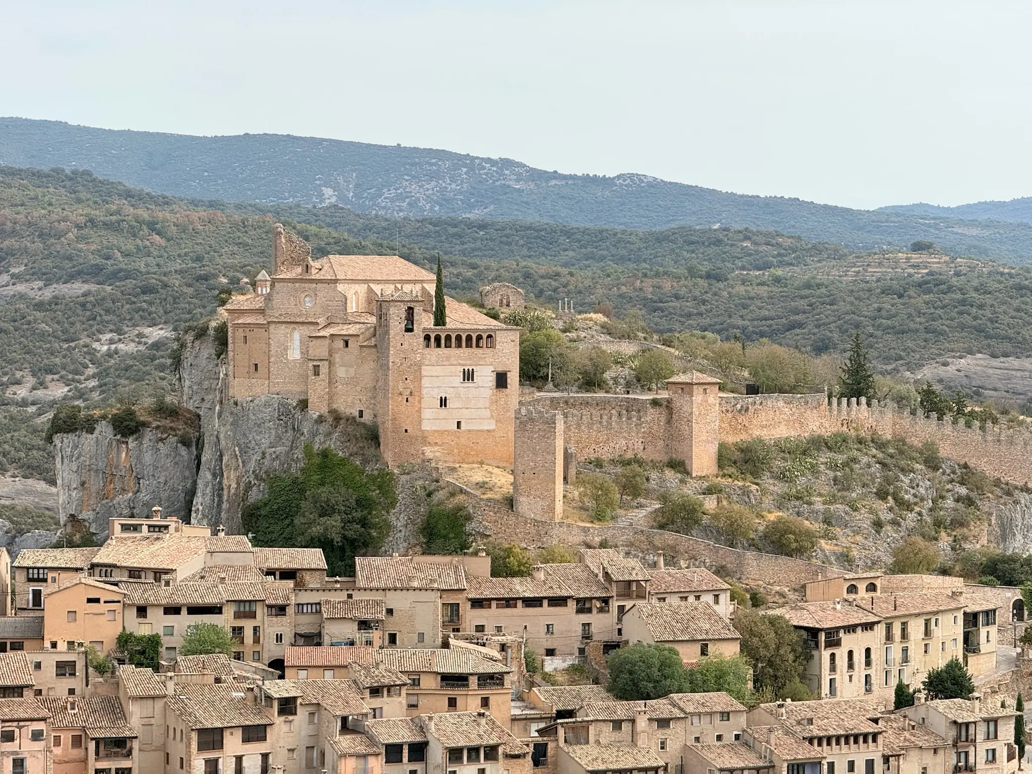 Colegiata de Santa María la Mayor de Alquézar sobre el peñasco con casas medievales y sierra al fondo