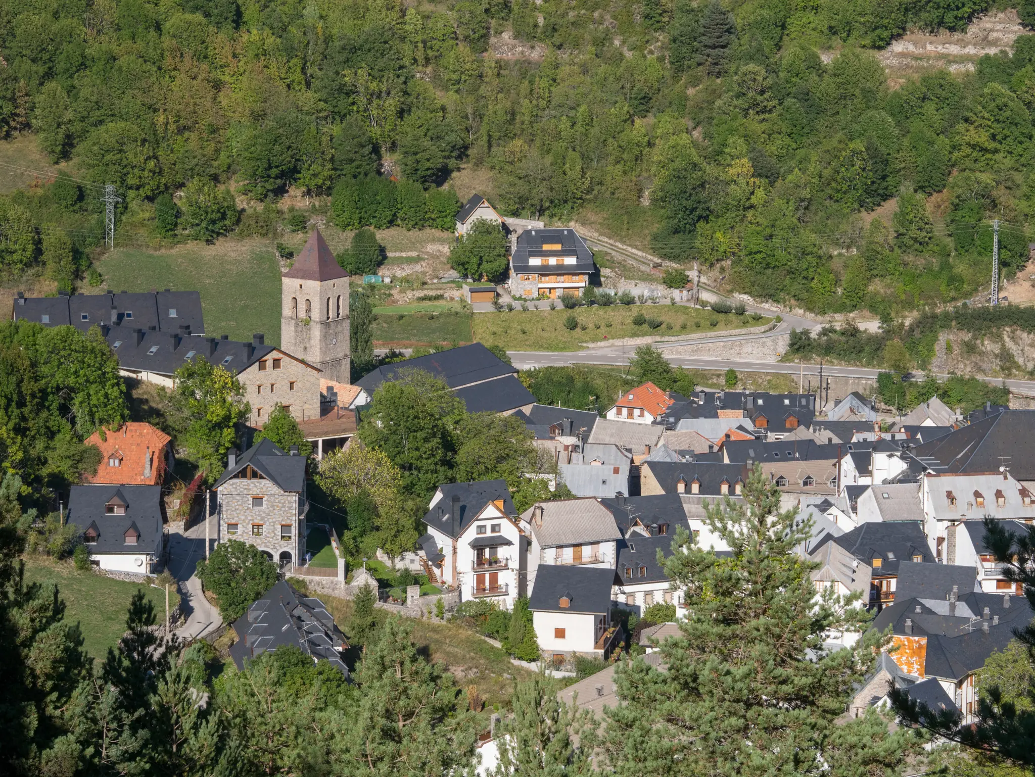 Vista aérea del pueblo de Bielsa en el Pirineo aragonés con su iglesia de torre característica rodeado de bosques verdes