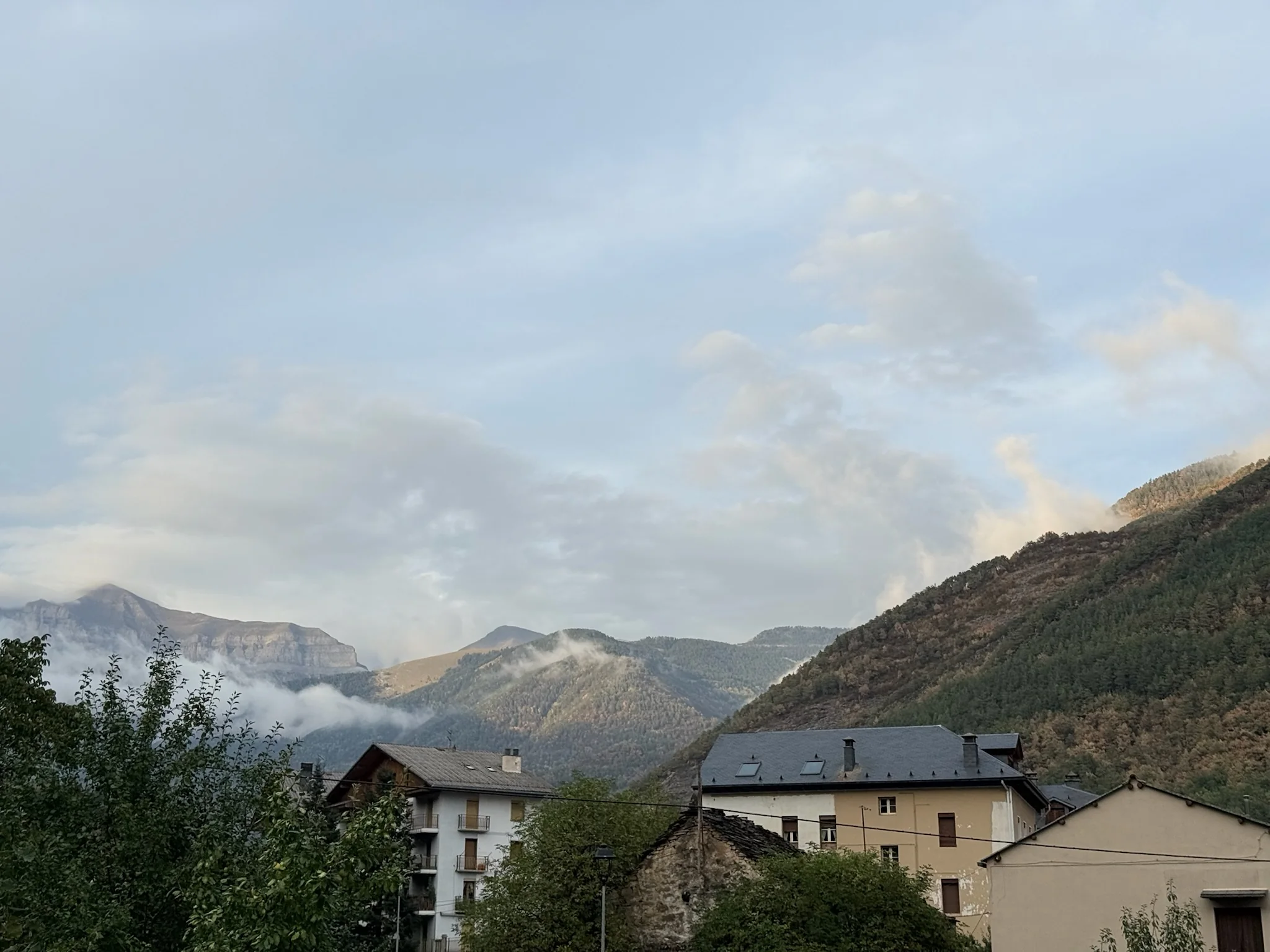Vista del pueblo de Broto con edificios y montañas del Parque Nacional de Ordesa con nubes bajas al fondo. Foto propia La Maleta Inquieta, octubre 2026