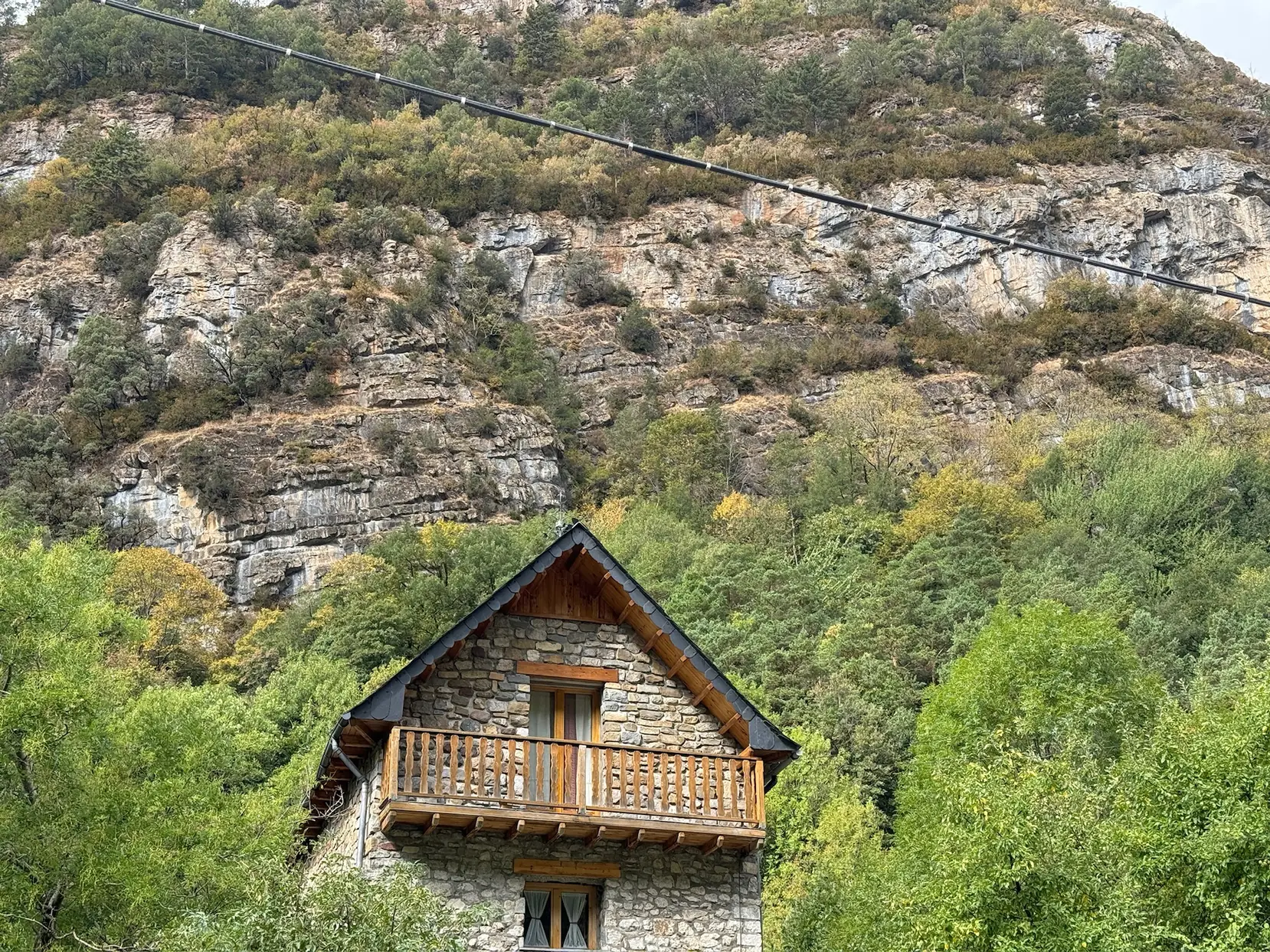 Casa de piedra con balcón de madera típica de Canfranc rodeada de vegetación y paredes rocosas al fondo. Foto propia La Maleta Inquieta, octubre 2026