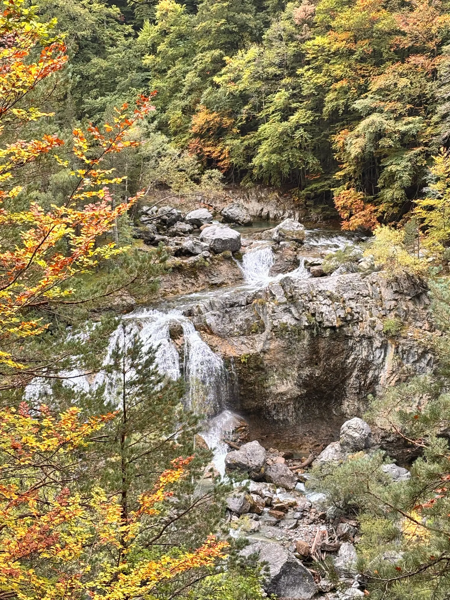 Cascada escalonada en dos niveles entre formaciones rocosas y bosque otoñal en Ordesa. Foto propia La Maleta Inquieta, octubre 2026