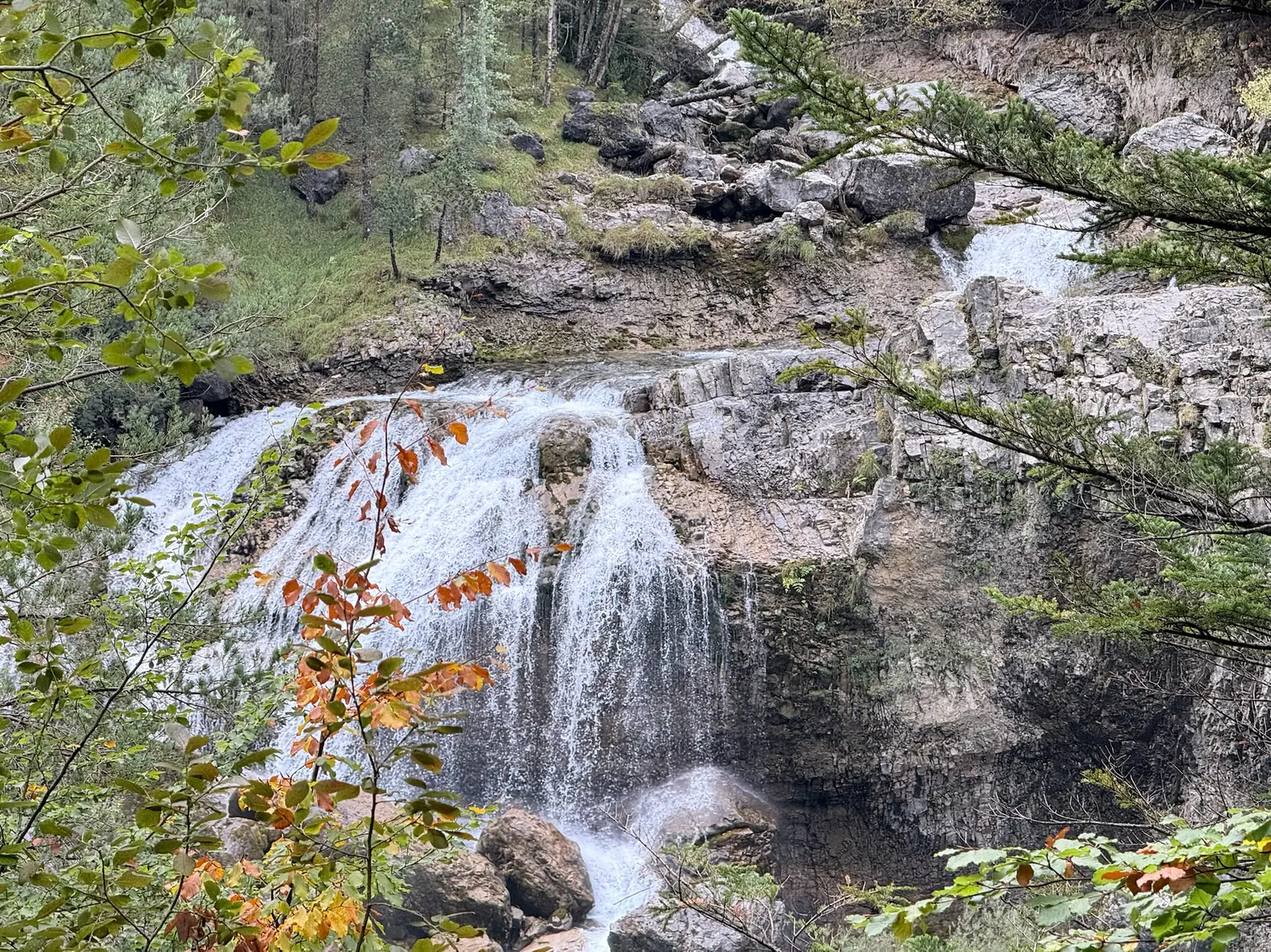 Cascada cayendo en varios niveles sobre roca caliza con vegetación otoñal en el valle de Ordesa. Foto propia La Maleta Inquieta, octubre 2026