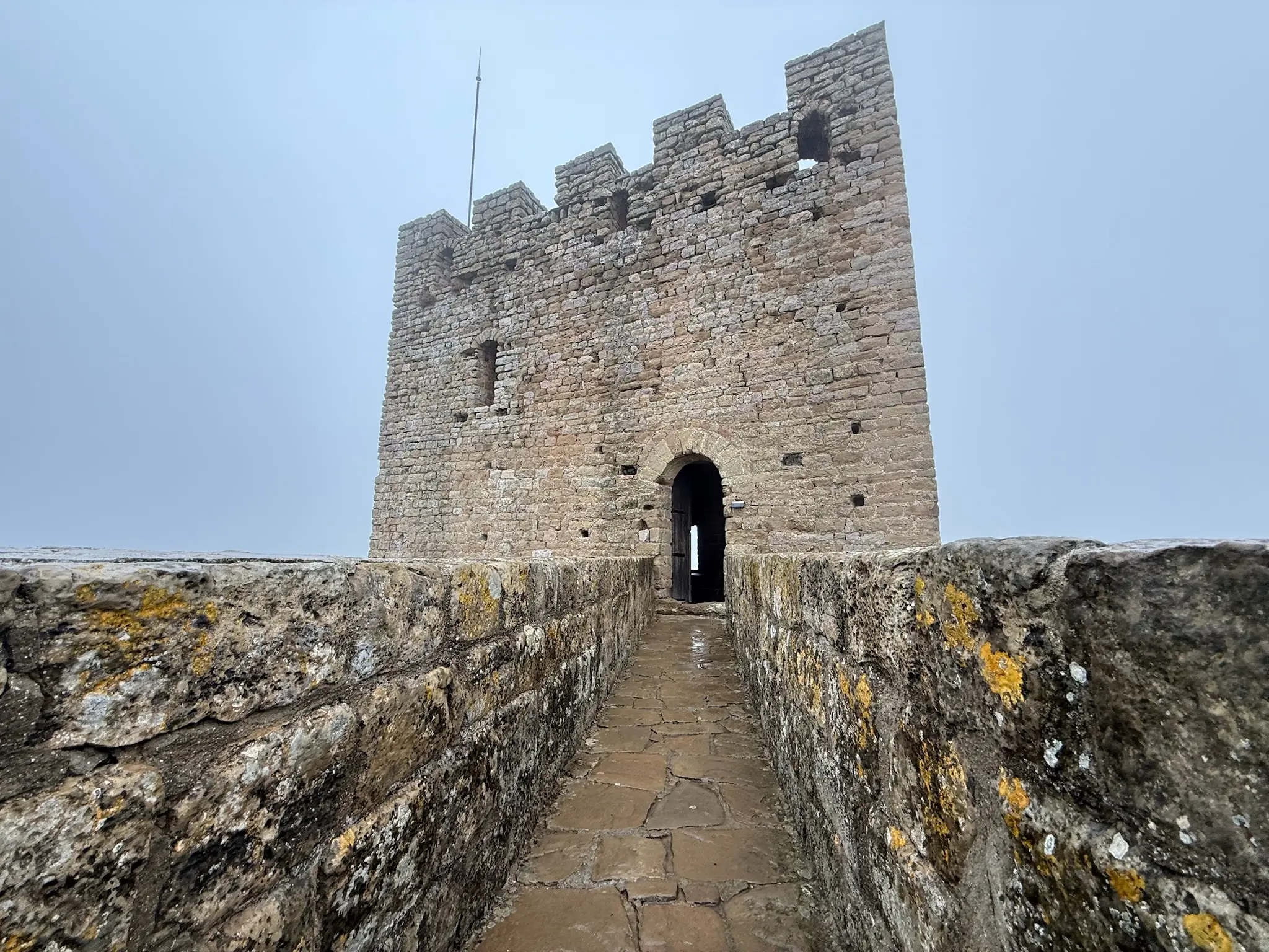 Paso de ronda del castillo de Loarre con almenas y torre del homenaje al fondo, muros con líquenes. Foto propia La Maleta Inquieta, octubre 2026