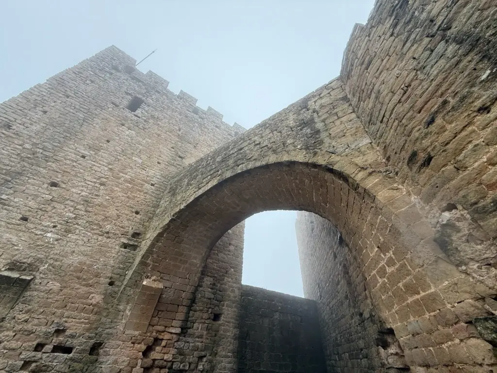 Vista desde abajo de arco de medio punto y torre del castillo de Loarre contra el cielo. Foto propia La Maleta Inquieta, octubre 2026
