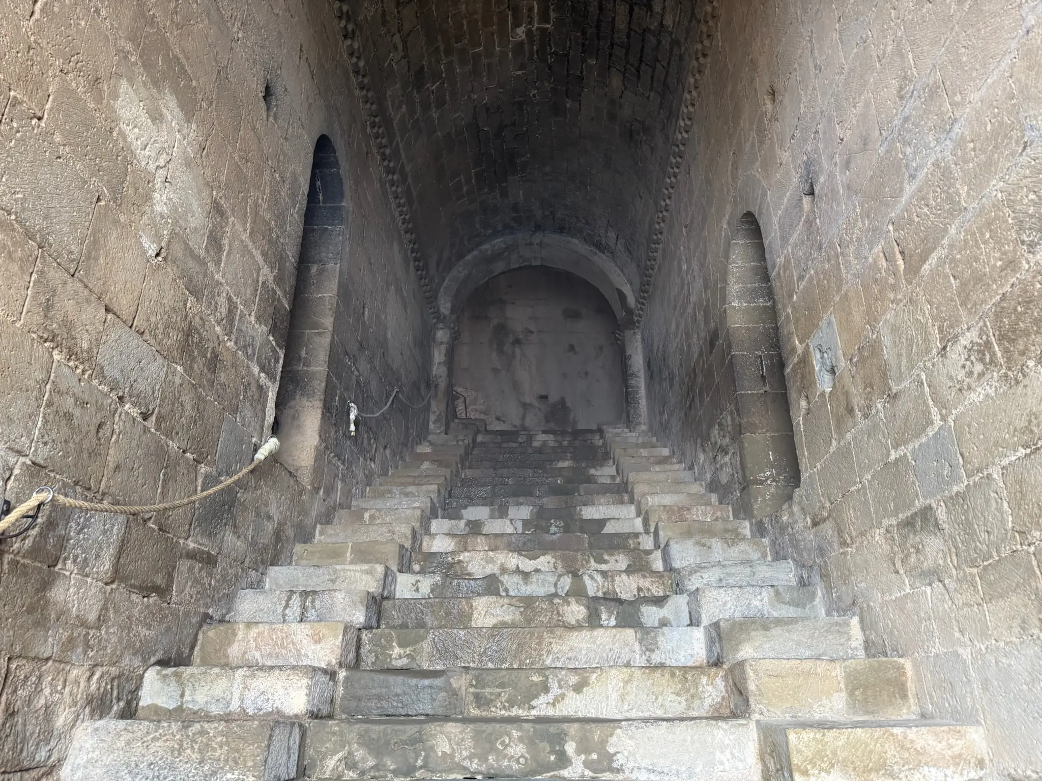 Escalera de piedra medieval vista desde arriba con arco y muros ennegrecidos en el castillo de Loarre. Foto propia La Maleta Inquieta, octubre 2026