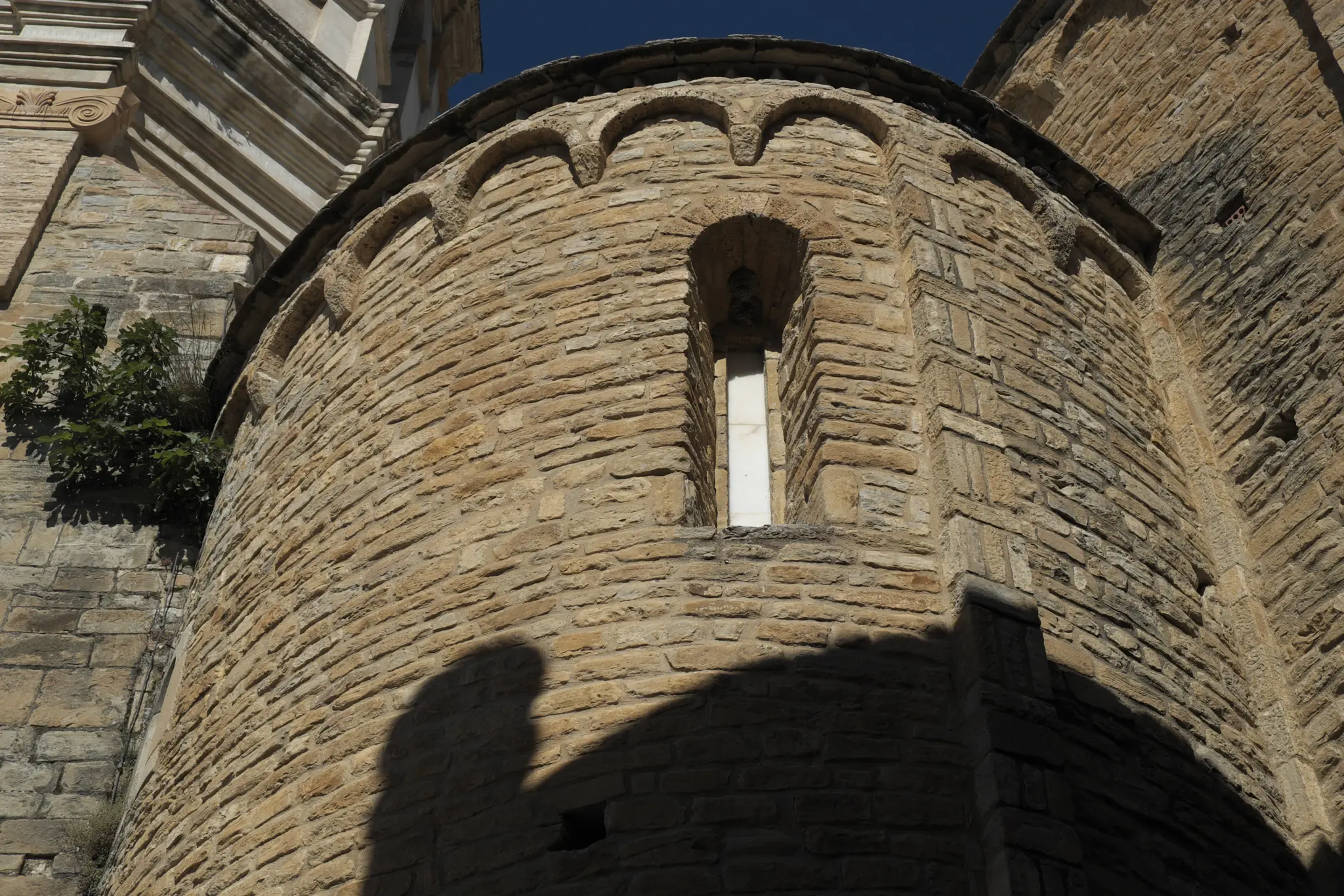 Ábside románico de la catedral de Roda de Isábena visto desde abajo con sillería de piedra arenisca y arquillos ciegos