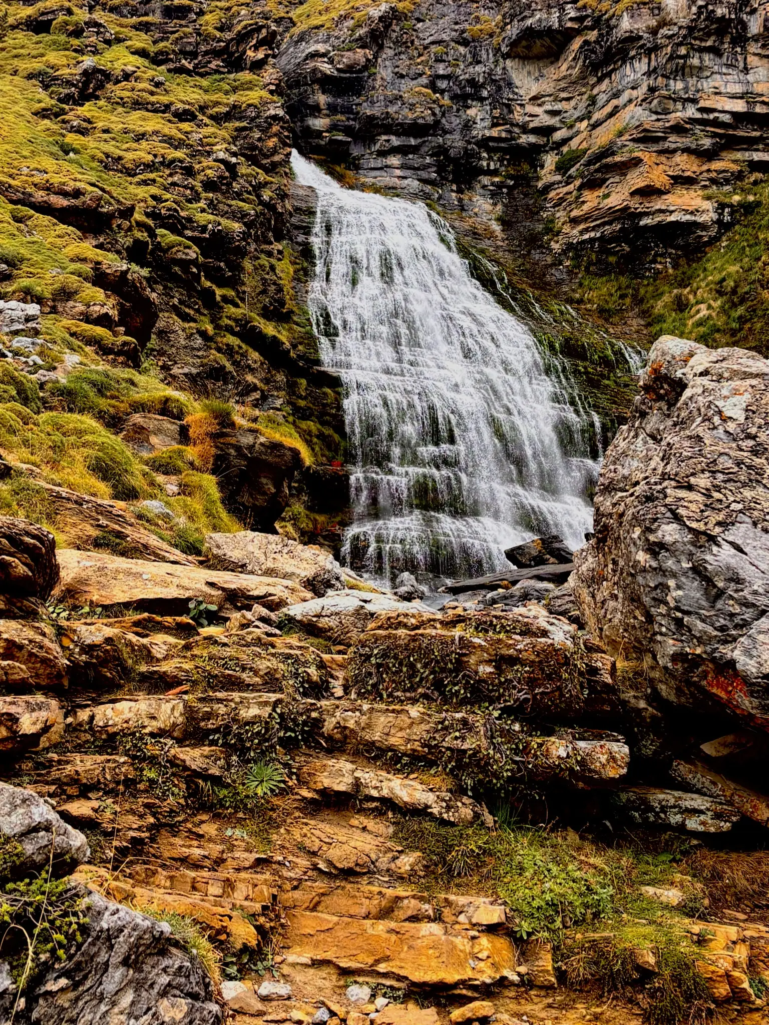 Cascada de la Cola de Caballo cayendo por la pared rocosa del Circo de Soaso, con rocas con musgo al pie. Foto propia La Maleta Inquieta, octubre 2026