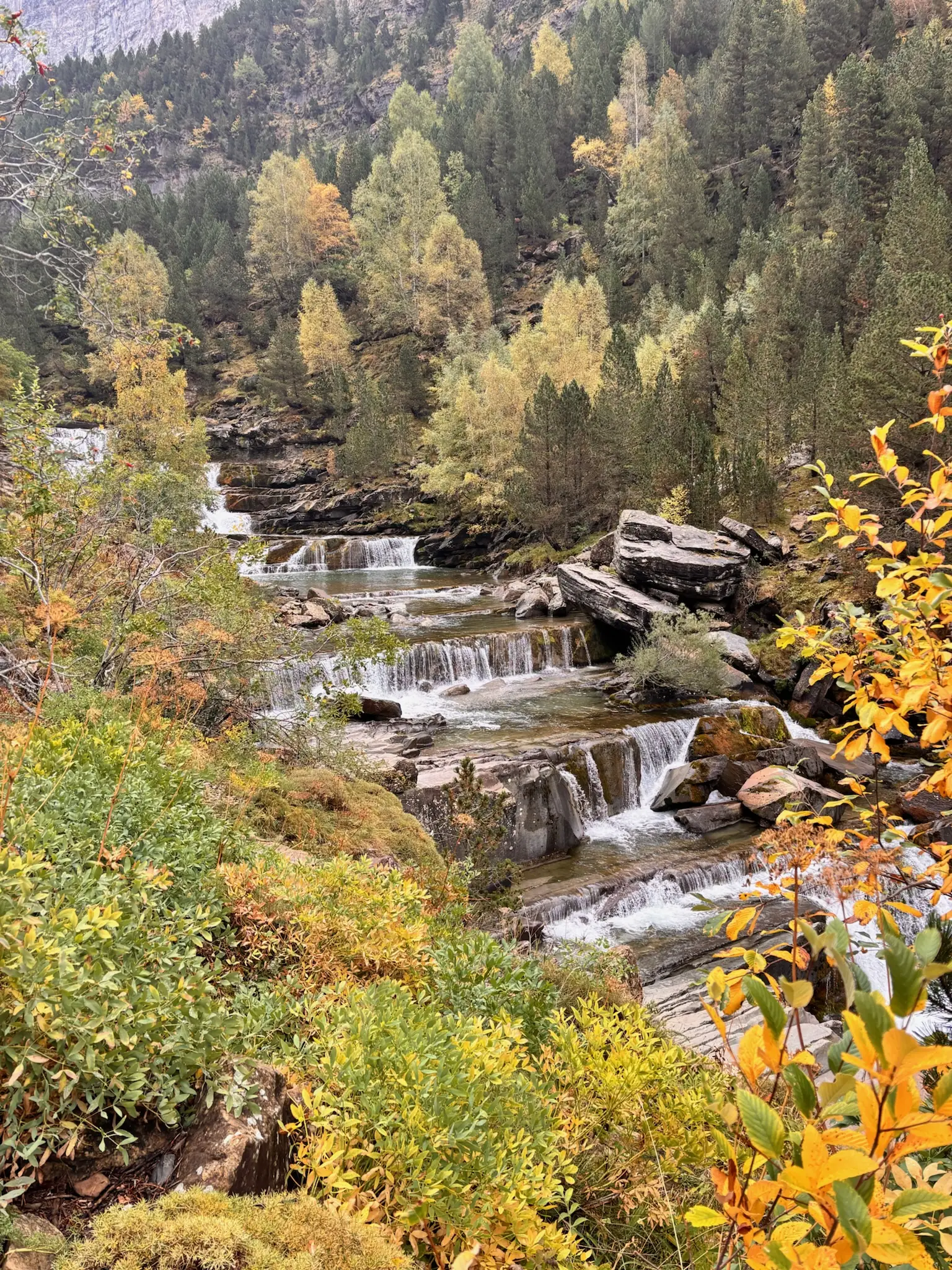 Saltos escalonados de agua entre rocas de las Gradas de Soaso con bosque otoñal al fondo. Foto propia La Maleta Inquieta, octubre 2026