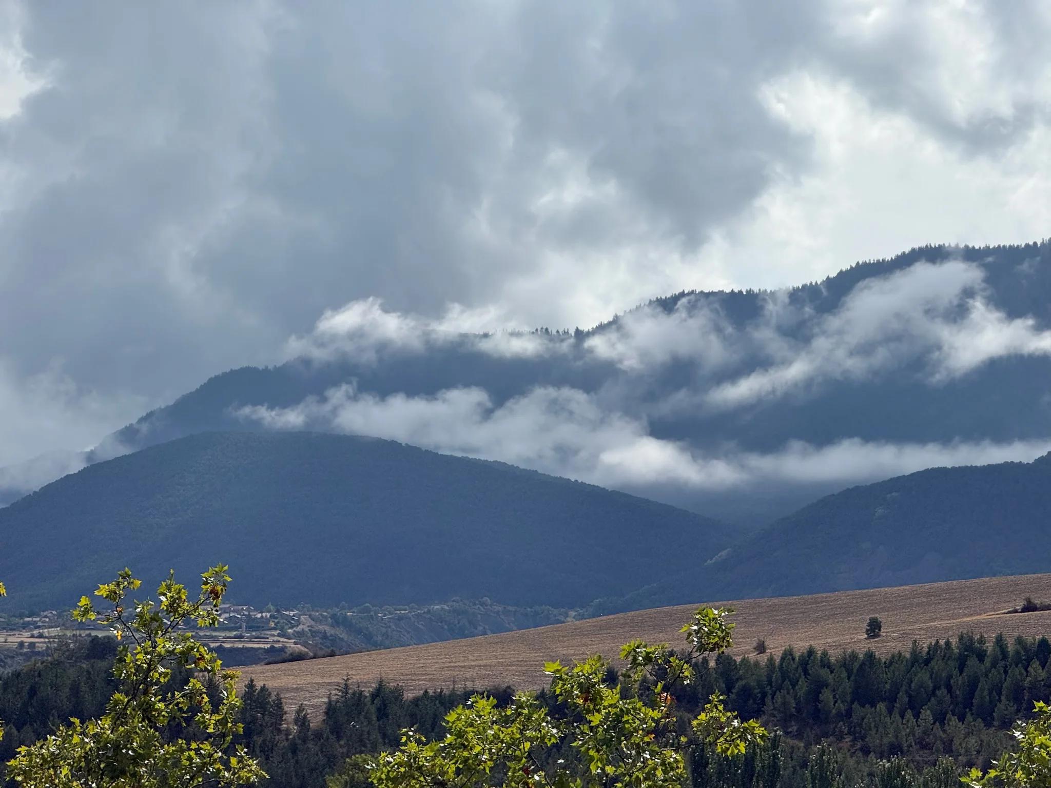 Montañas del Pirineo con nubes bajas, campos cultivados y bosques en el entorno de Jaca. Foto propia La Maleta Inquieta, octubre 2026