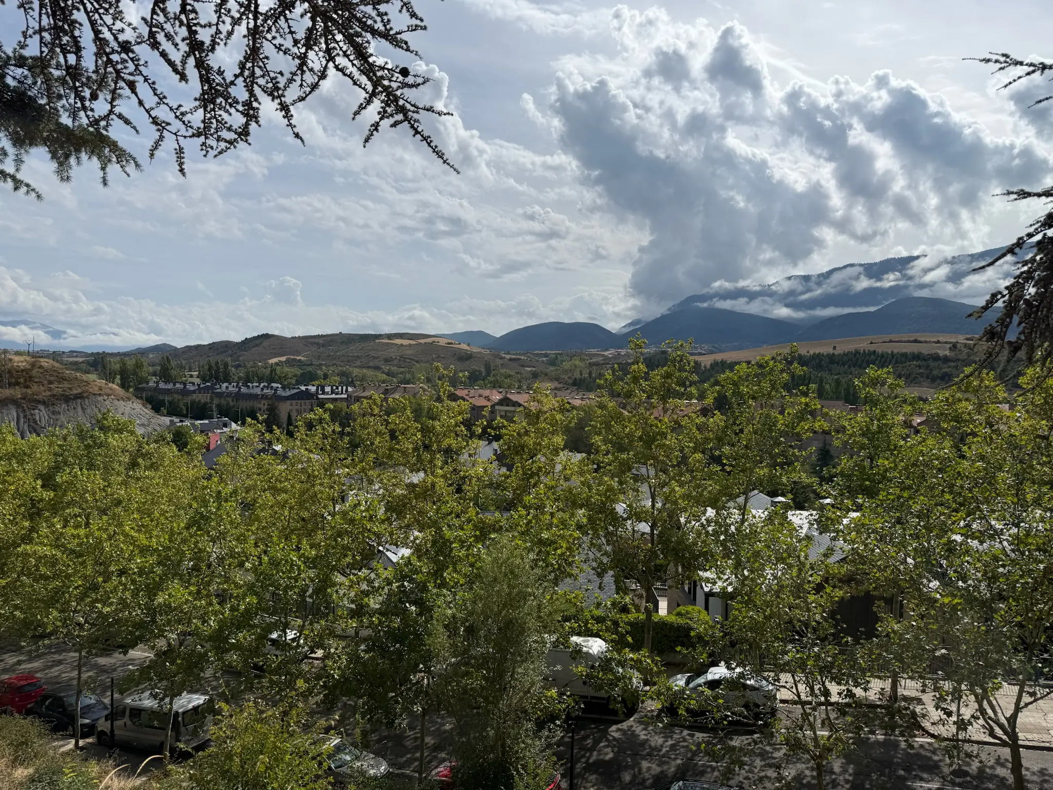 Vista panorámica de Jaca desde altura con tejados del pueblo y montañas pirenaicas con nubes dramáticas. Foto propia La Maleta Inquieta, octubre 2026