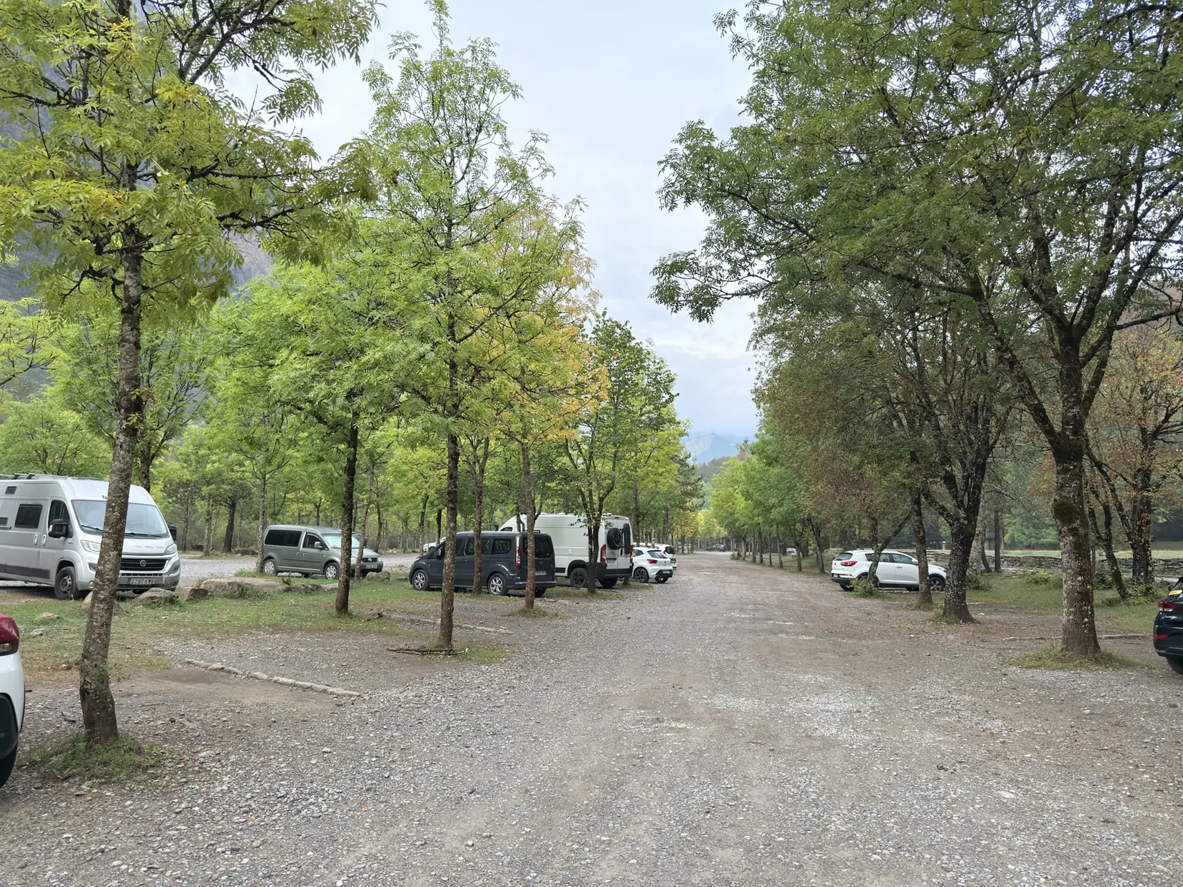 Aparcamiento del Parque Nacional de Ordesa con vehículos bajo árboles y montañas al fondo. Foto propia La Maleta Inquieta, octubre 2026