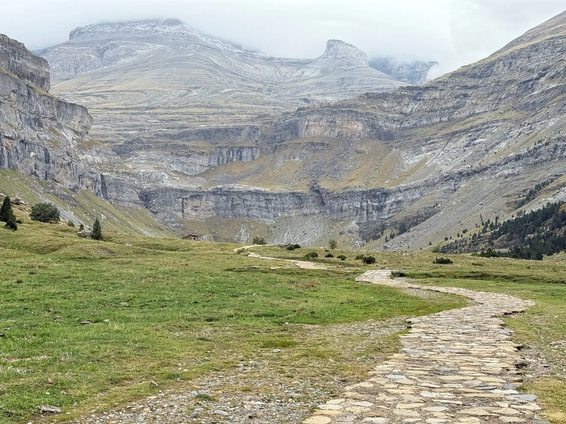 Valle de Ordesa con sendero empedrado entre prados verdes y paredes rocosas estratificadas del circo de Soaso. Foto propia La Maleta Inquieta, octubre 2026