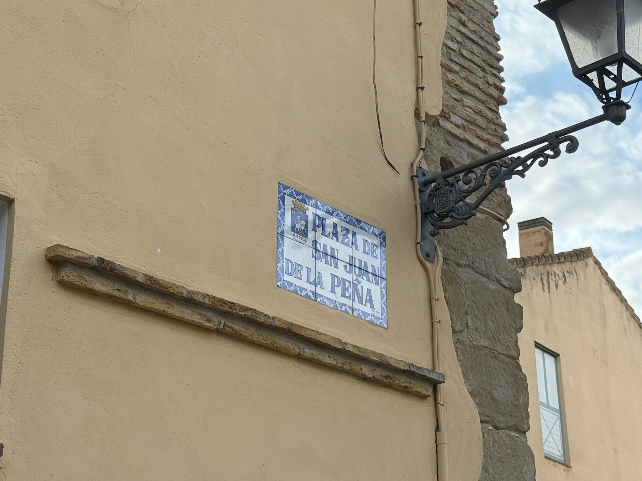 Placa de calle de cerámica azul con el nombre Plaza de San Juan de la Peña en el casco antiguo de Huesca. Foto propia La Maleta Inquieta, octubre 2026
