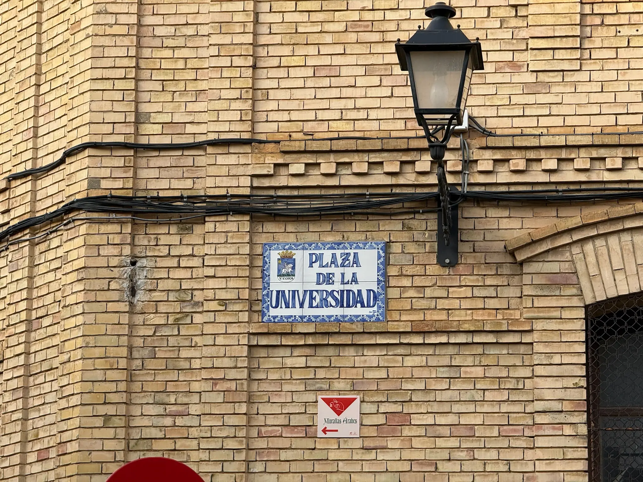 Placa de cerámica azul de la plaza de la Universidad y señal de las murallas árabes en Huesca. Foto propia La Maleta Inquieta, octubre 2026