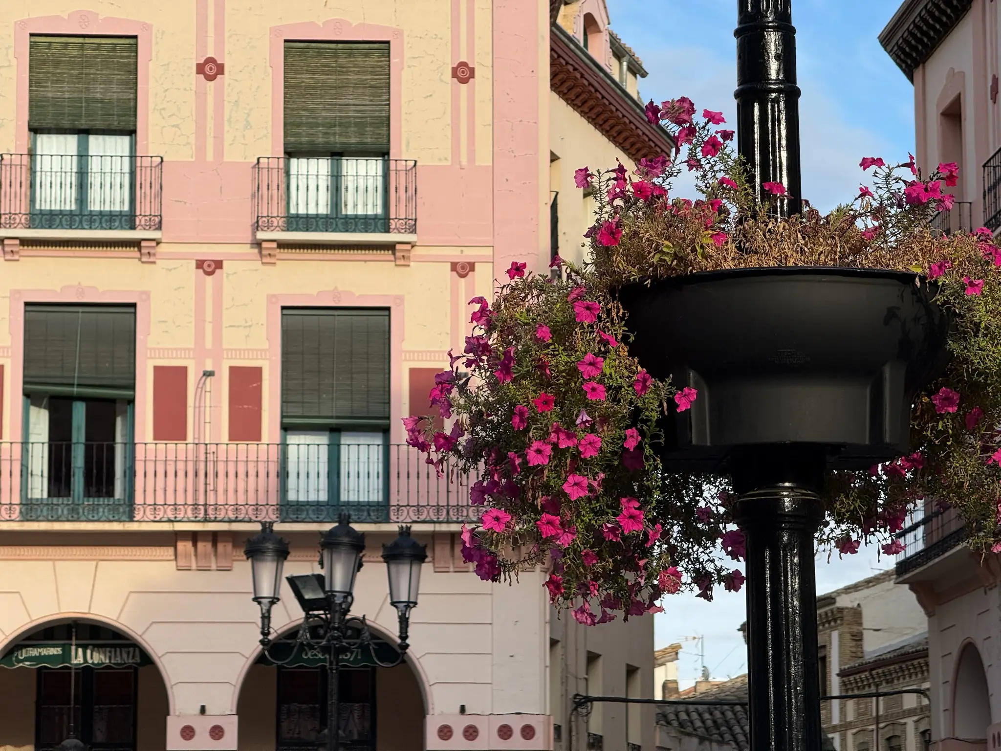 Edificio de fachada rosa con flores colgantes en farola de la Plaza López Allué, Huesca. Foto propia La Maleta Inquieta, octubre 2026
