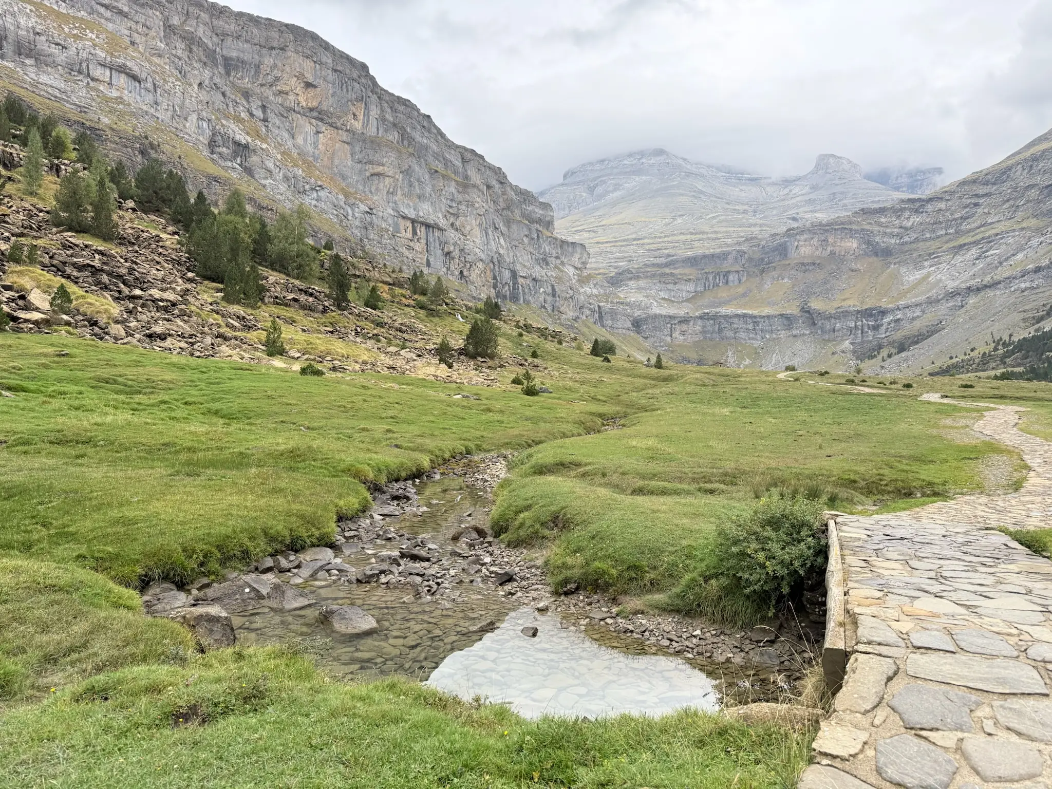 Pradera verde del circo de Soaso con riachuelo y camino empedrado rodeada de paredes rocosas. Foto propia La Maleta Inquieta, octubre 2026