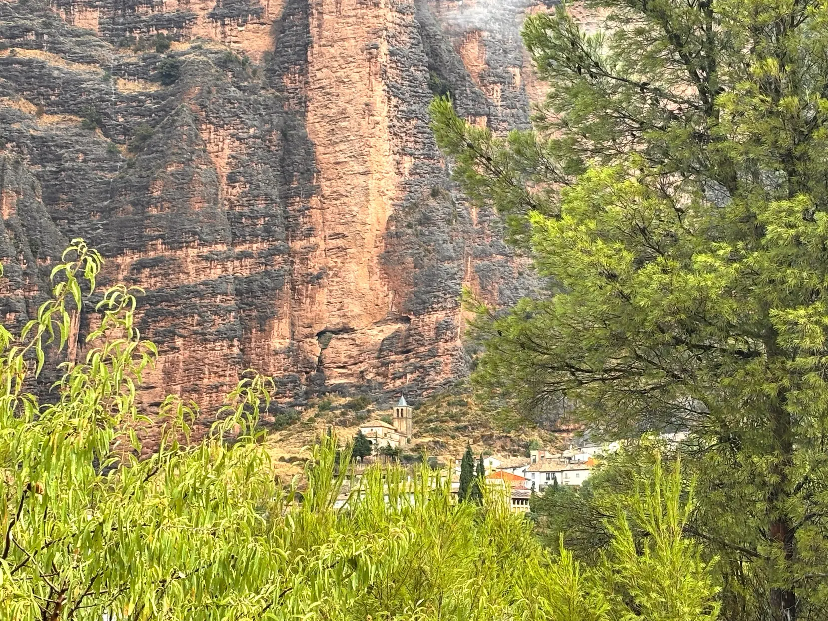 Pueblo de Riglos con su iglesia al pie de las formaciones rocosas rojizas estratificadas de los mallos. Foto propia La Maleta Inquieta, octubre 2026