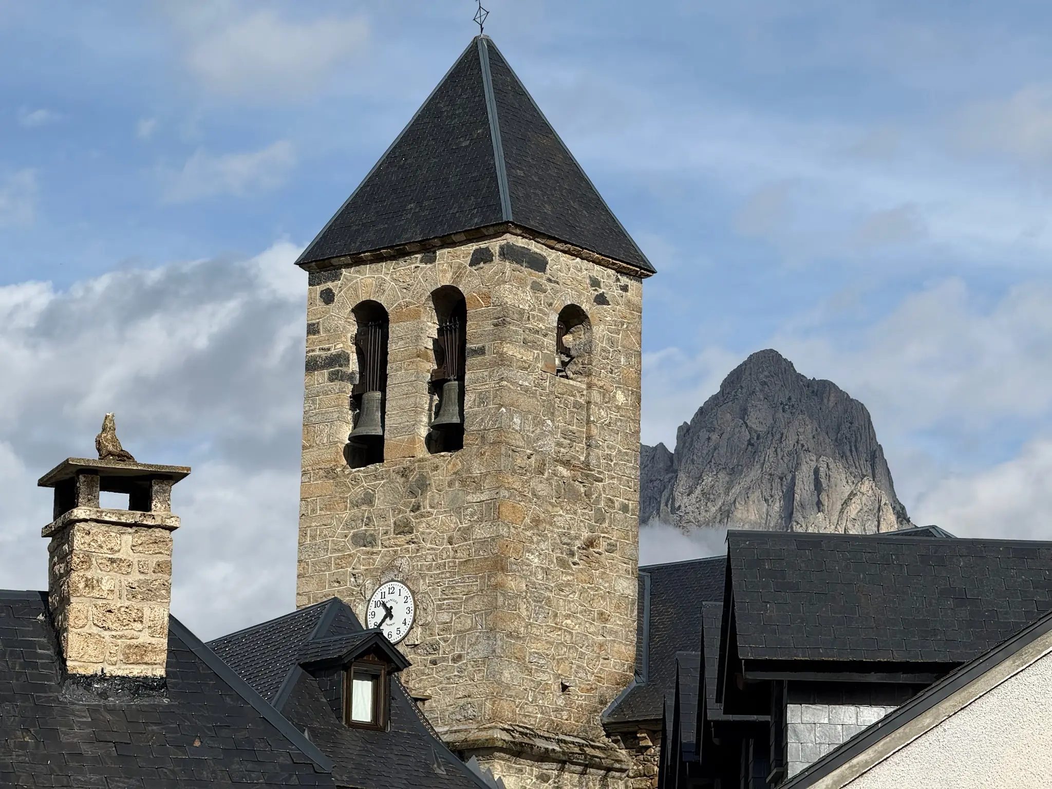 Torre campanario de piedra con reloj en Sallent de Gállego y la Peña Foratata al fondo. Foto propia La Maleta Inquieta, octubre 2026