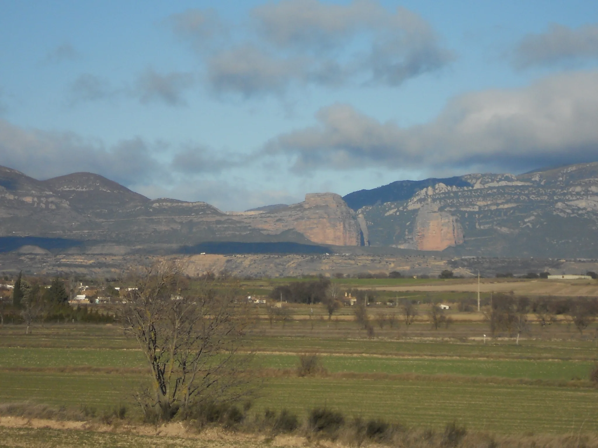 Vista del Salto de Roldán con su característica formación rocosa de paredes estratificadas sobre campos de cultivo bajo cielo nublado