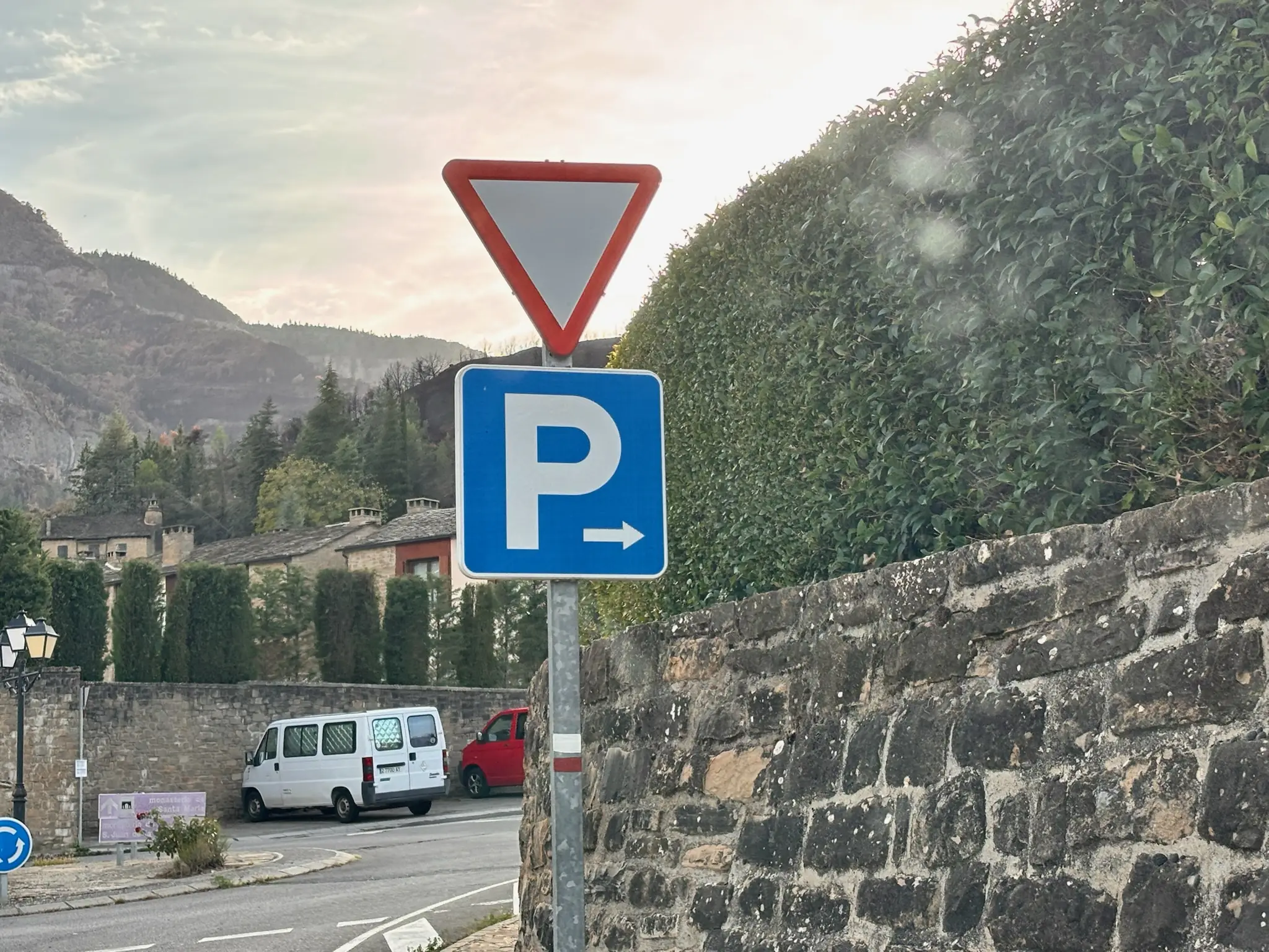 Señal de parking junto a una muralla de piedra oscura en Santa Cruz de la Serós, con tejados de pizarra. Foto propia La Maleta Inquieta, octubre 2026