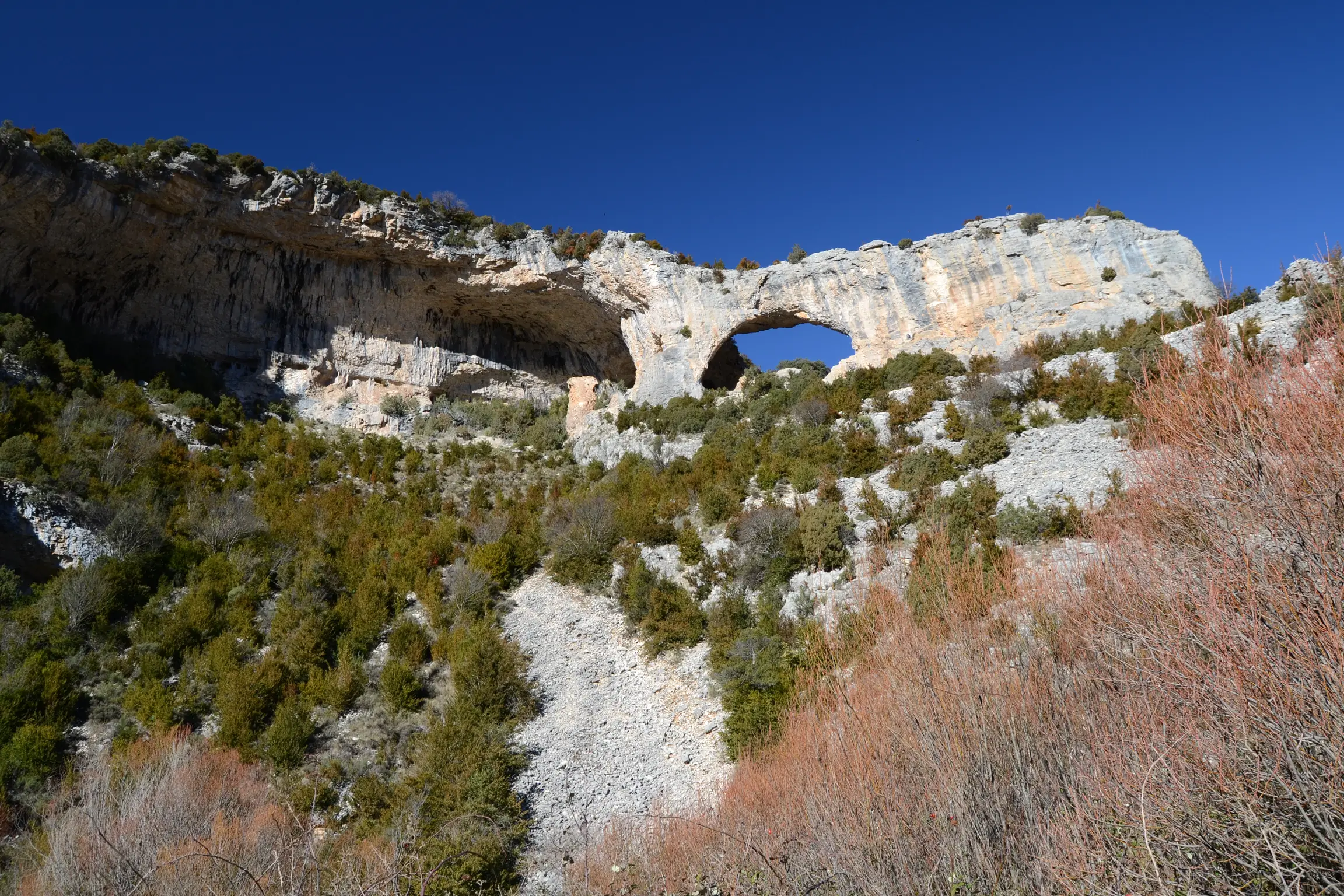 Formación rocosa con arco natural en el barranco del Mascún Inferior en la Sierra de Guara con vegetación